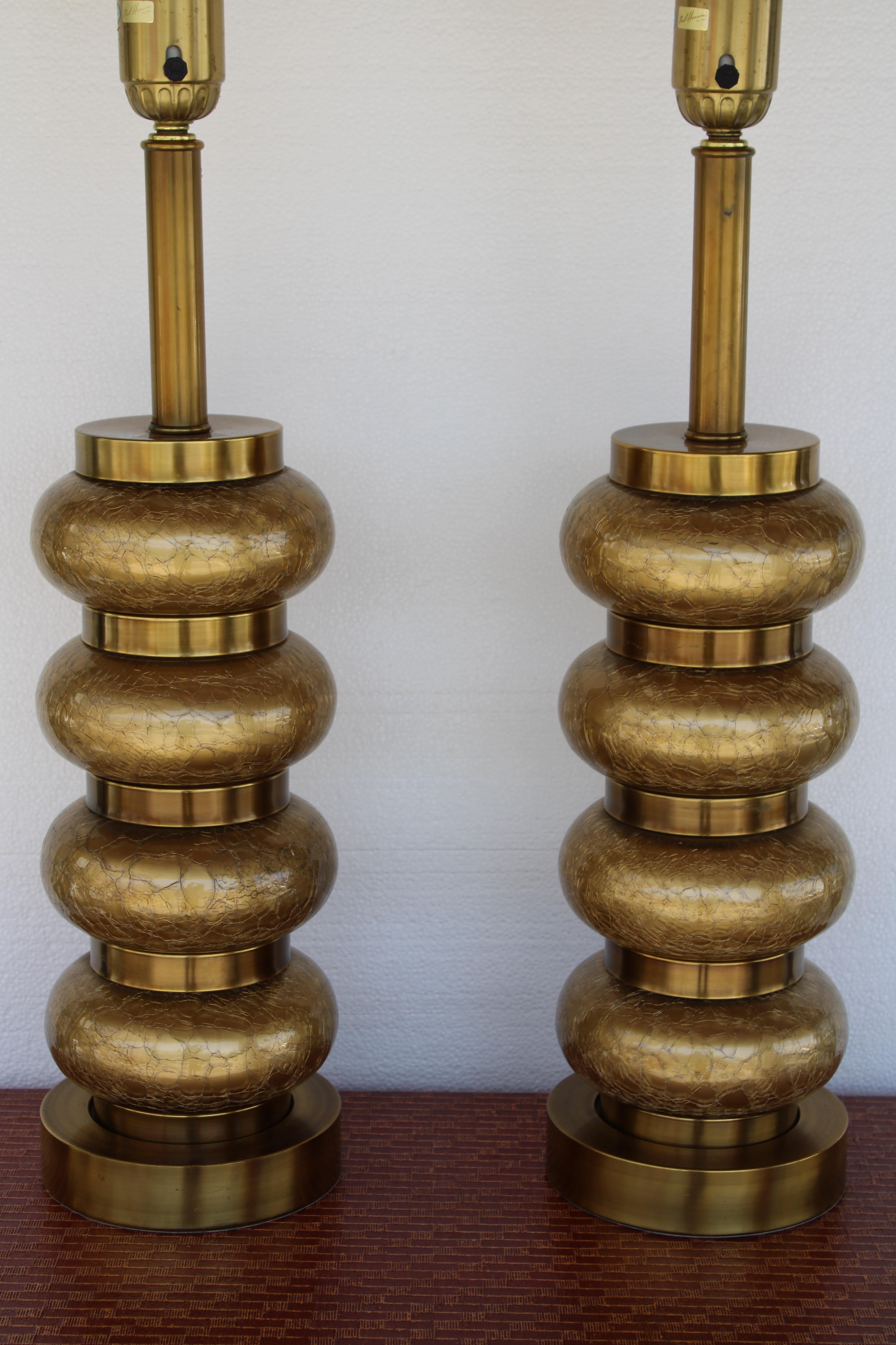 Pair of reverse gilt and brass table lamps by Paul Hanson Co. They consist of four alternating bands of gilt crackle glass ovals and patinated brass rings. Lamp measures 36.5