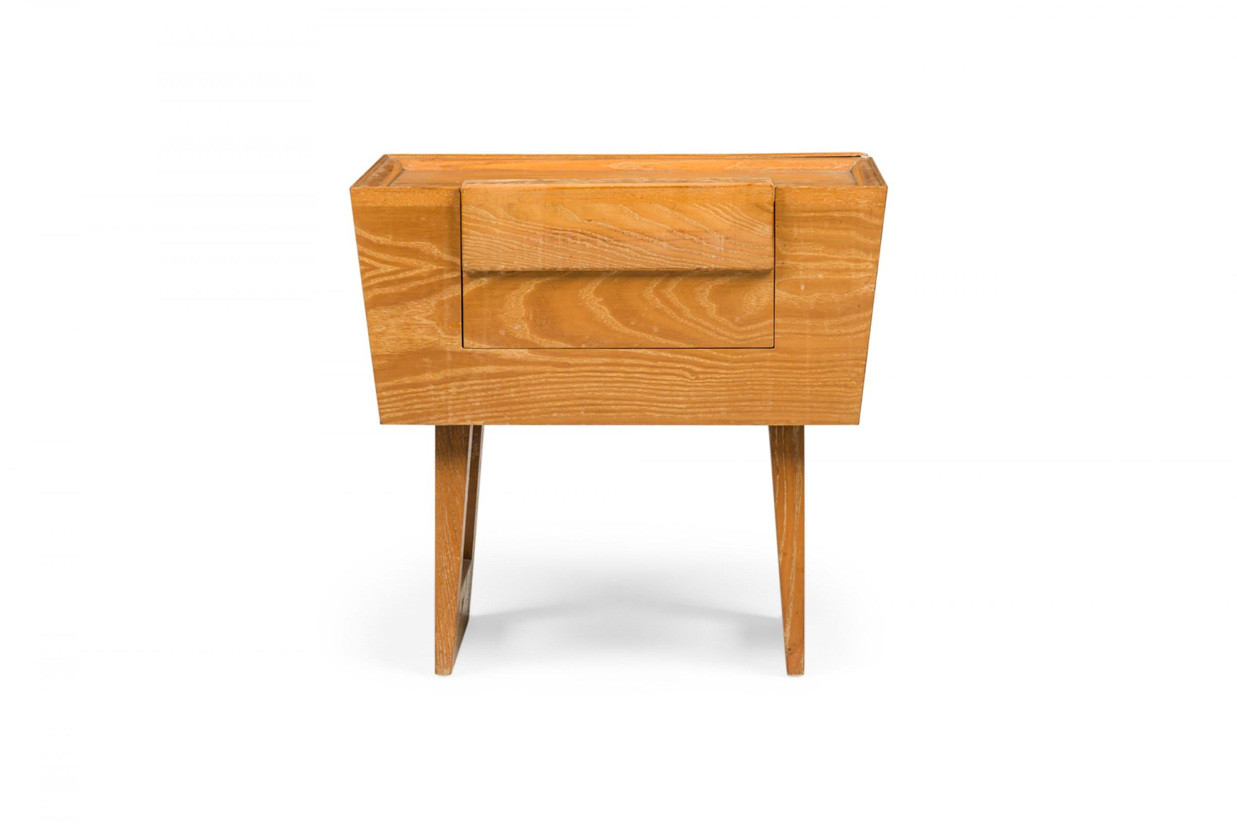 PAIR of American Mid-Century light wooden nightstands with tapered trapezoidal cabinets containing a single drawer, resting on two bracket-shaped legs. (PAUL LASZLO FOR BROWN SALTMAN)(PRICED AS PAIR)(Similar pieces: DUF0738, DUF0739).