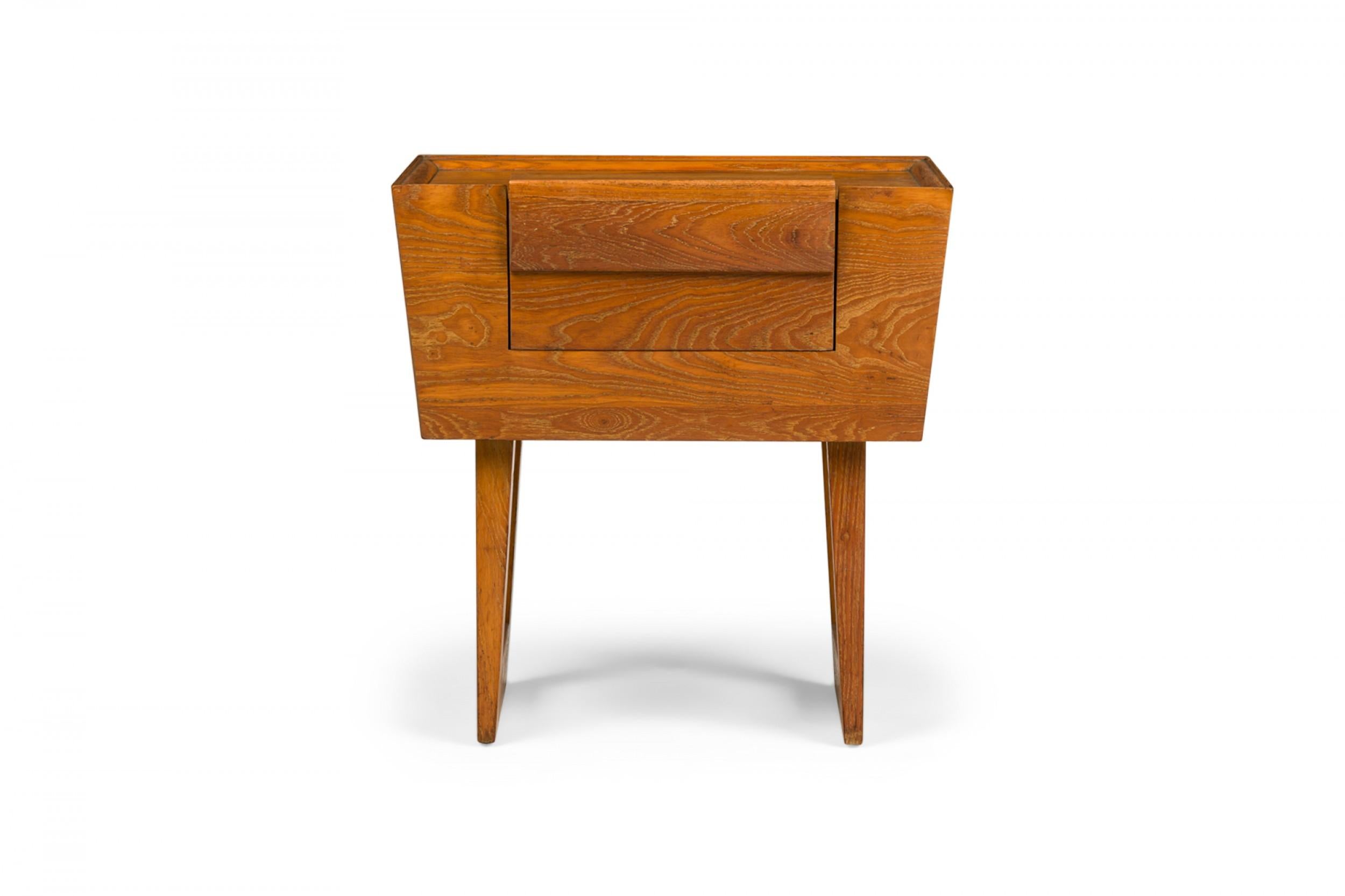 PAIR of American Mid-Century wooden nightstands with tapered trapezoidal cabinets containing a single drawer, resting on two bracket-shaped legs. (PAUL LASZLO FOR BROWN SALTMAN)(PRICED AS PAIR)(Similar pieces: DUF0738, DUF0740).