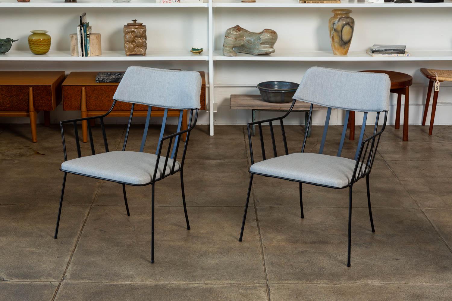 A pair of rare patio dining armchairs by Paul Laszlo for Pacific Iron Products, circa 1950s. The chairs feature a black iron frame with newly upholstered seat and upper back in a light grey Sunbrella fabric. This chair was part of a suite of three