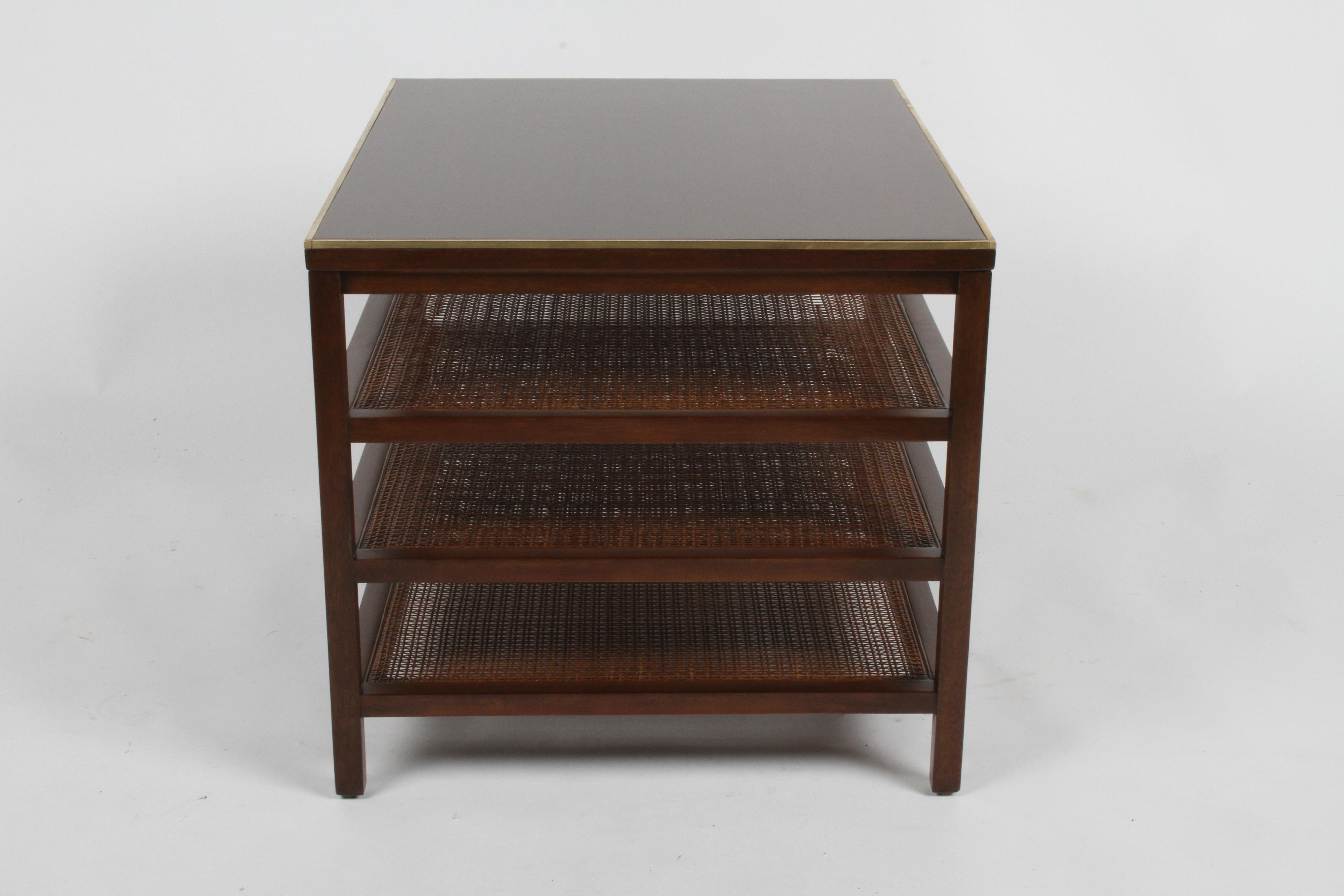 Pair of Paul McCobb for Directional three tiered end tables or magazine stands (model 8738), mahogany frames, with contrasting caned shelves and brass edge to top. Refinished in a medium espresso finish, brass polish, some minor loss to caning.