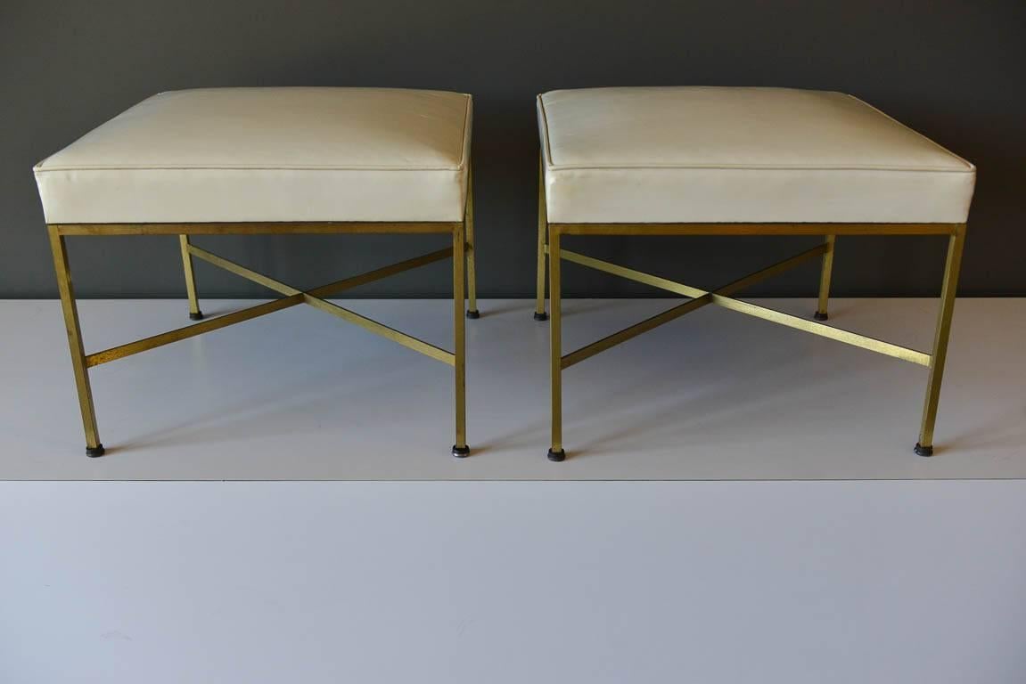 Original pair of model 1306 ottomans or stools by Paul McCobb for Directional. Brass X-base stretcher bars with original ivory vinyl cushions. Could use as stools, bench, ottoman or free floating seating.  All feet are original. 

Measure 20