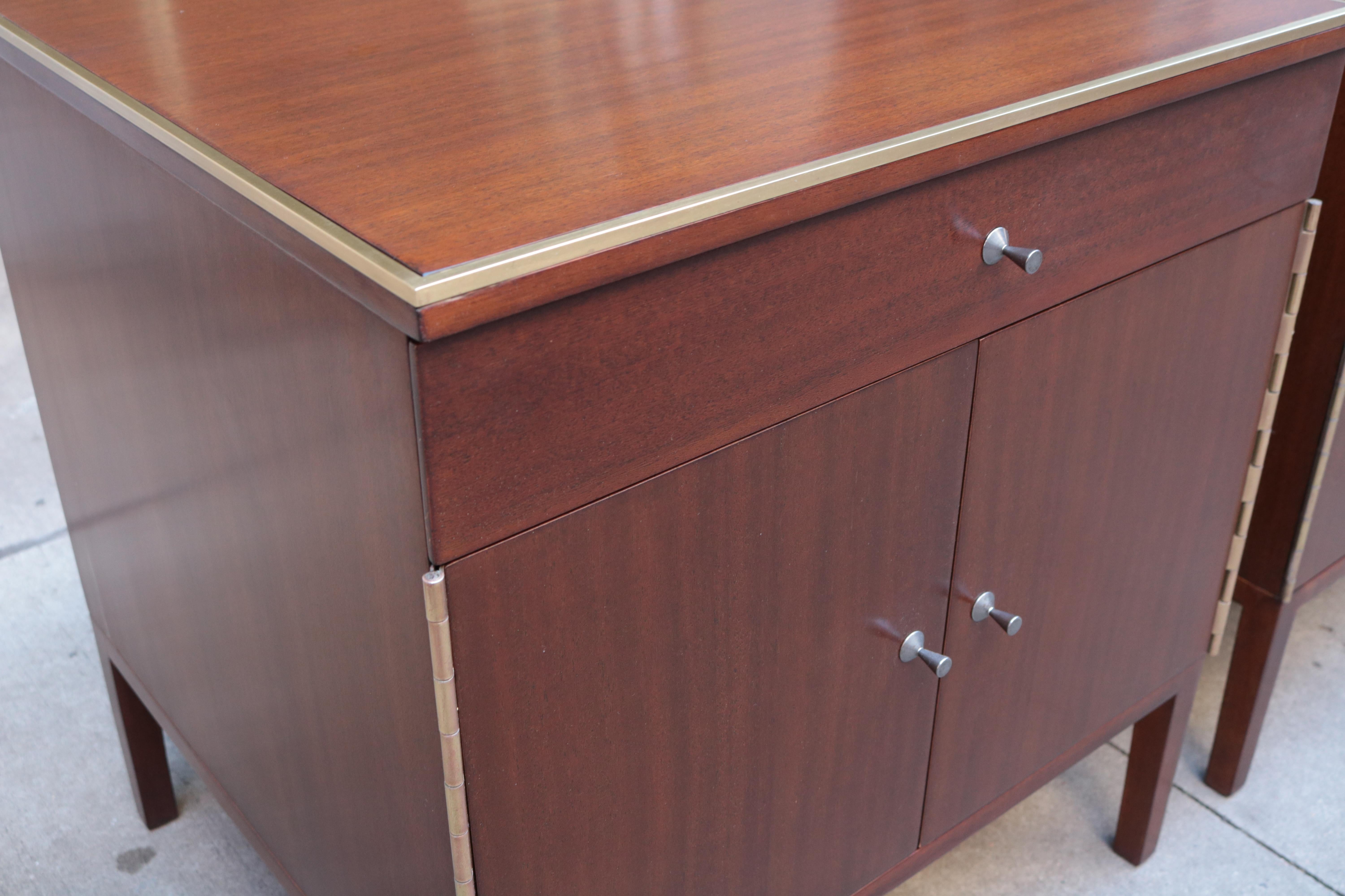 A pair of Paul McCobb designed modernist side cabinets. 
Mahogany with brass trim details and nickel pulls. 
With original label.