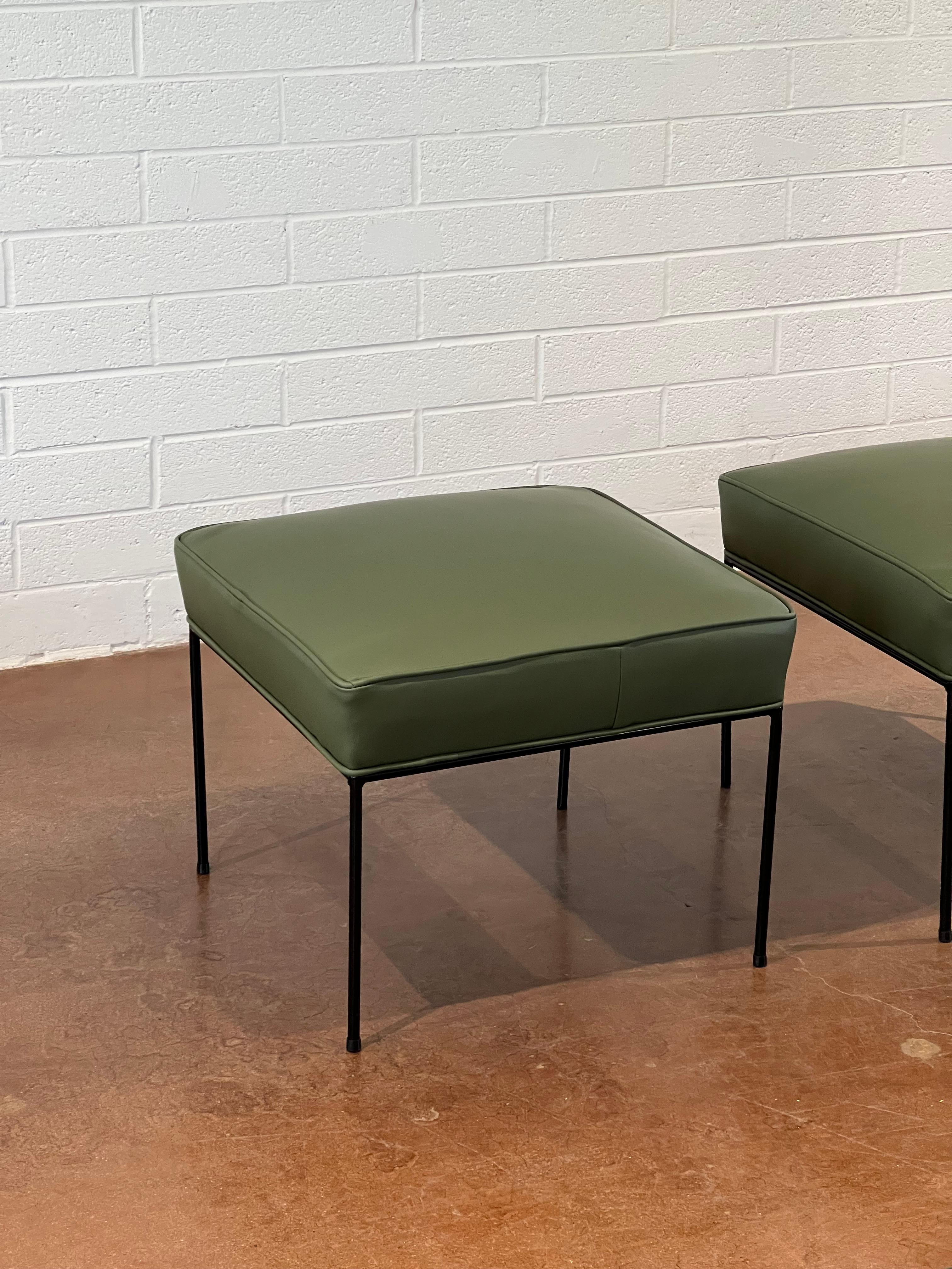 This set of 2 Paul McCobb ottomans have been reupholstered with new green leather. The original iron legs are in great condition. 