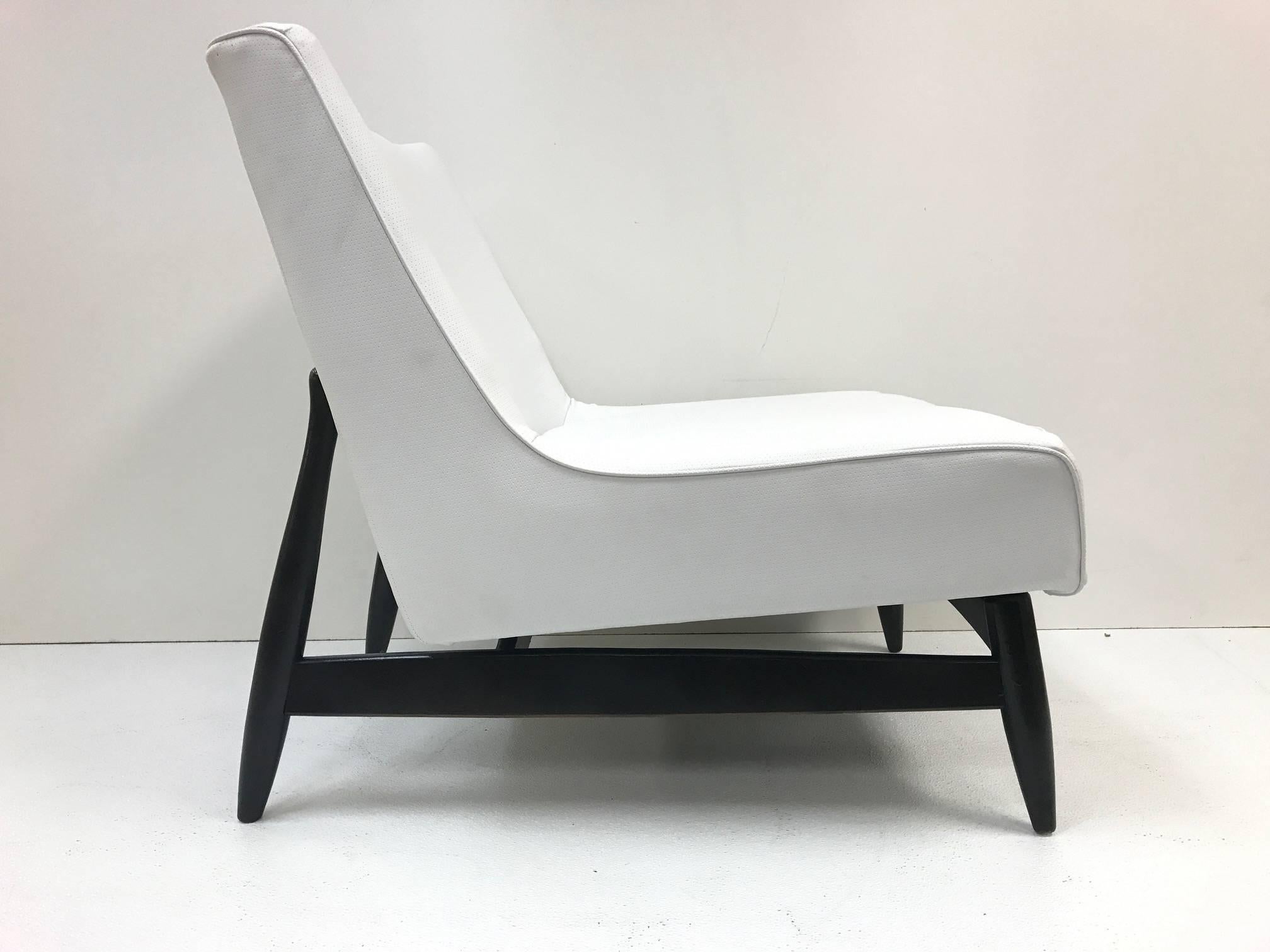 Pair of Paul McCobb style lounge chairs. Chairs have black lacquered frames with white leatherette upholstery.