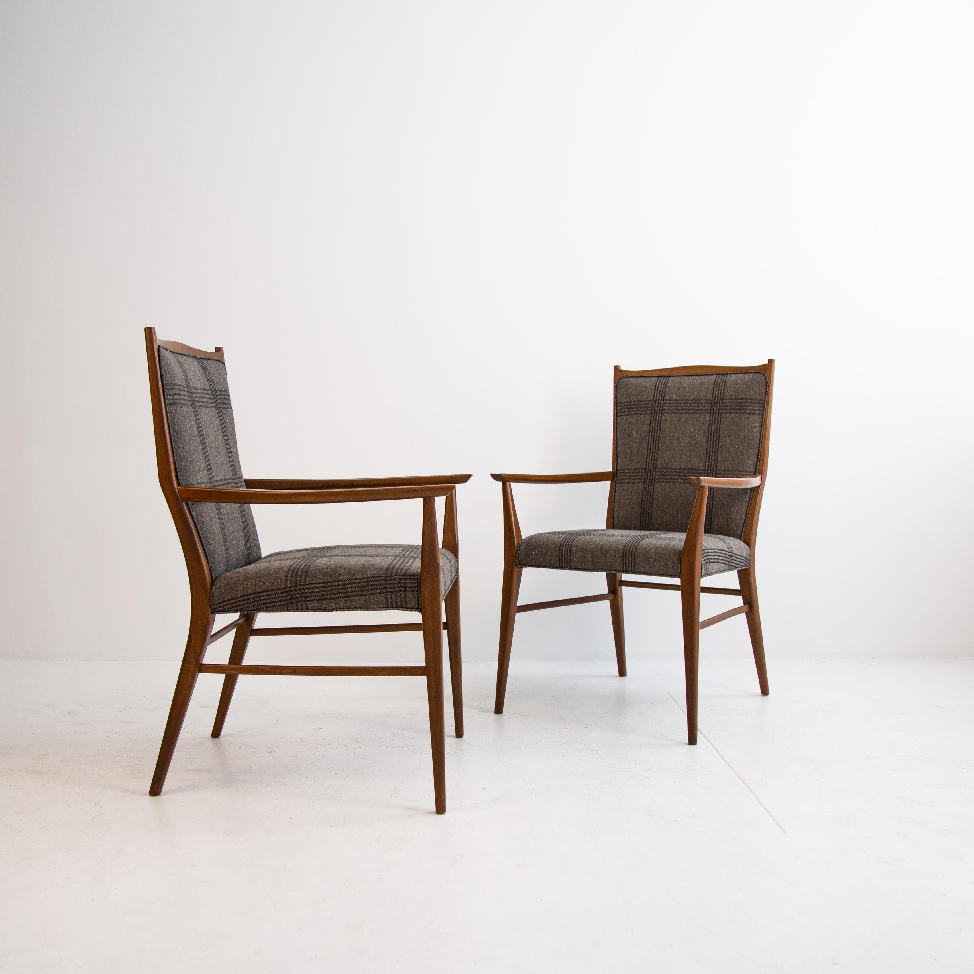 A delicate pair of Danish Mid-Century Modern Paul McCobb upholstered armchairs newly reupholstered in grey and black linen with a fully restored wood frame stained in dark walnut. The chairs feature an elegant curvature to the legs, armrest, and