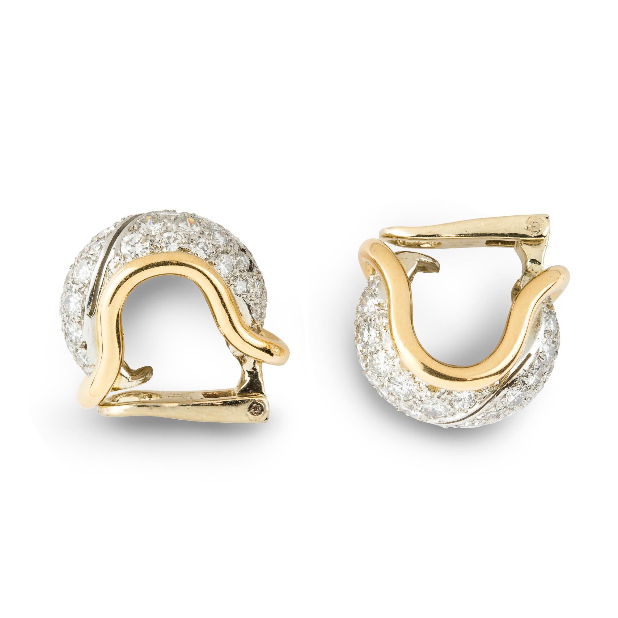 A pair of diamond hoop clip earrings, each earring comprising of a pavé-set diamond centre, estimated to weigh a total of 2.2 carats for the pair, with a pierced diagonal stripe and a yellow gold border, all to a white gold mount with clip fittings,