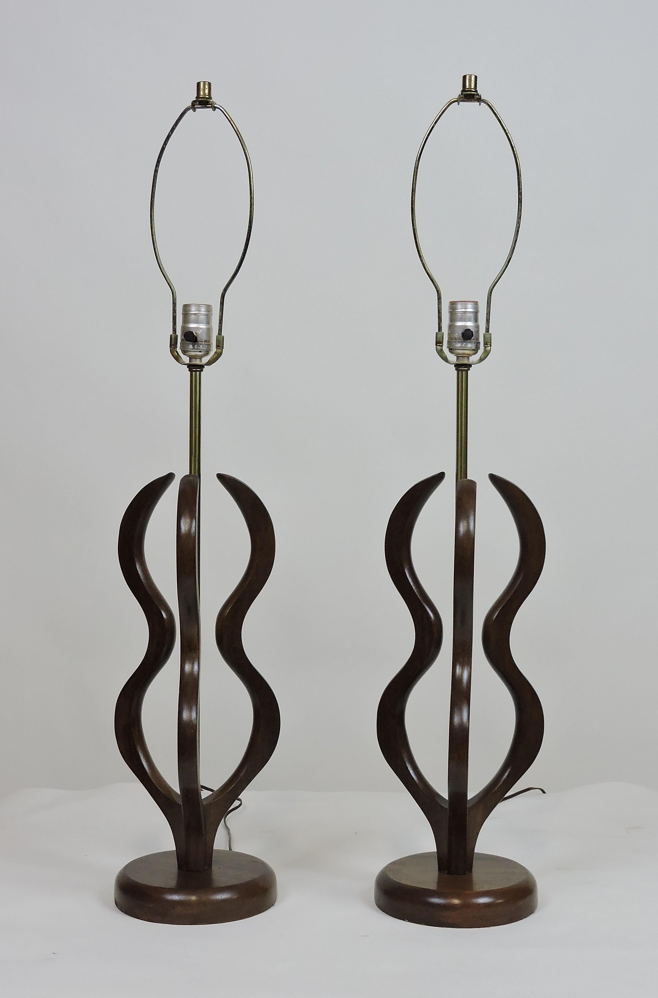 Pair of large sized midcentury Pearsall or Modeline style table lamps. These lamps are made of wavy formed sculpted walnut and have the original nubby fabric shades.