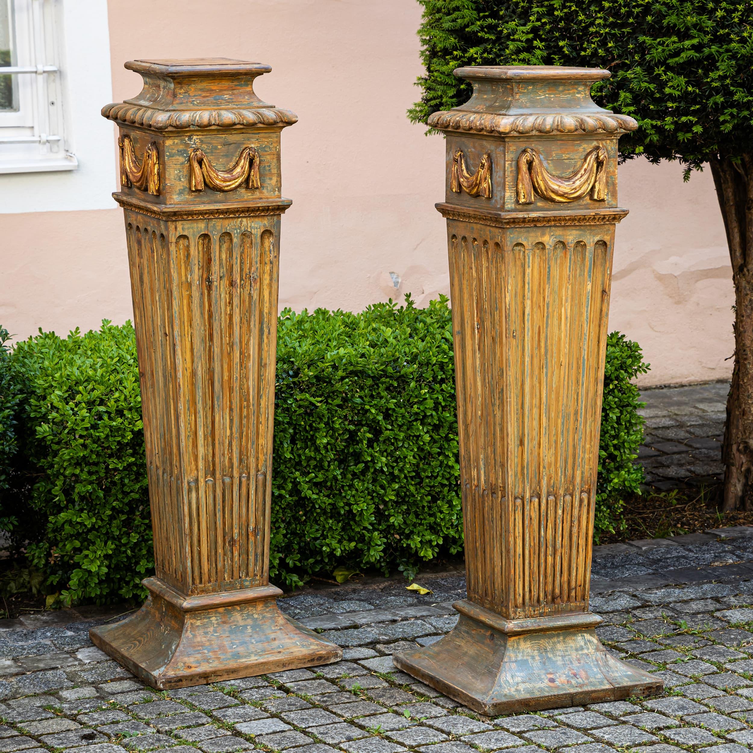 Elegante pareja de pedestales de estilo neoclásico, del siglo XX. El diseño y la decoración de inspiración clásica recuerdan a los modelos antiguos y los hacen ideales para exponer esculturas, bustos o jarrones.