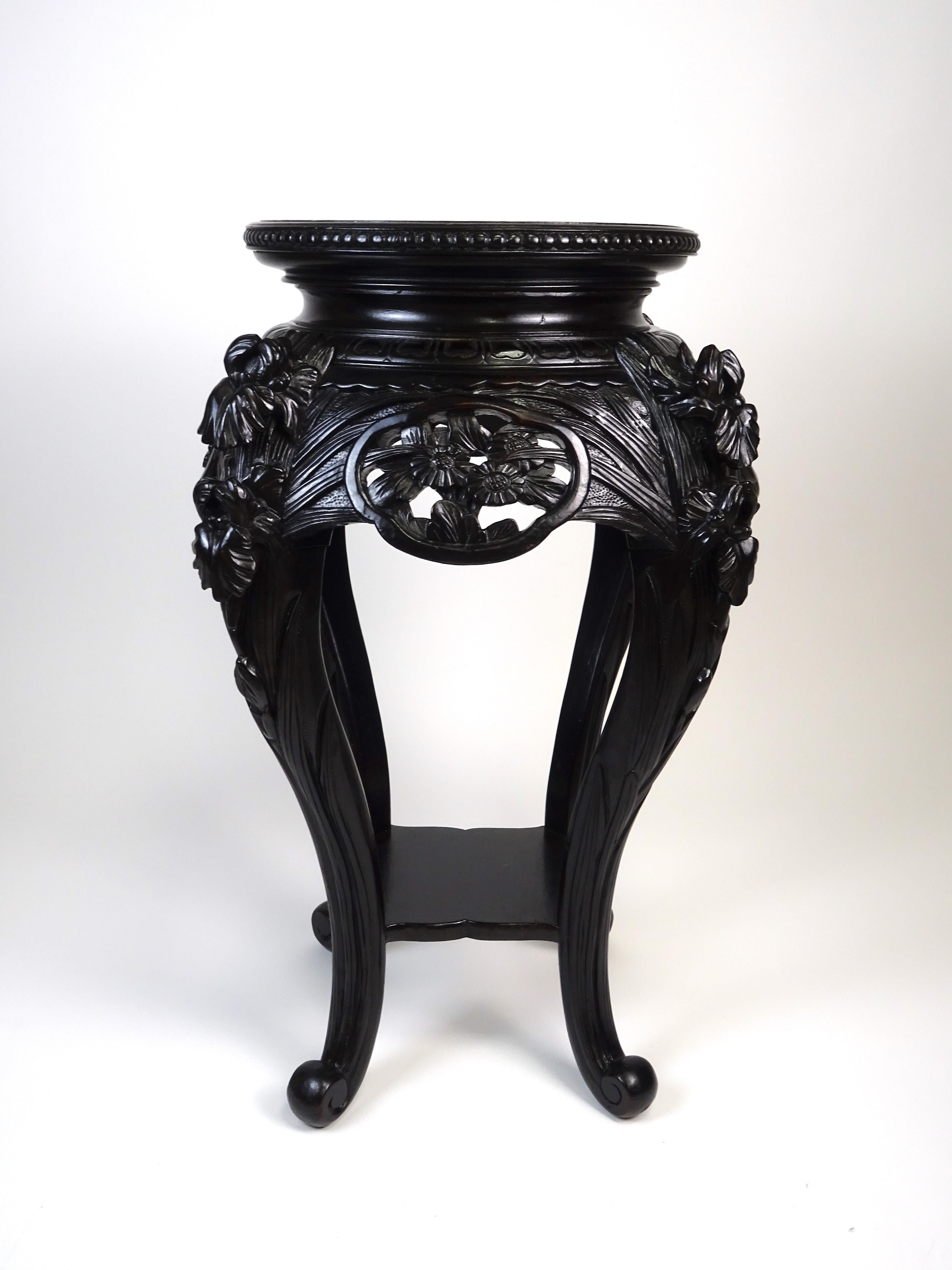 Pair of Chinese-made pedestals/pot stands, datable to the early 20th century.

The two pieces of furniture are made of carved ebonized oak, and are thus presented in a deep black color. There are geometric patterns on the circular top, while floral
