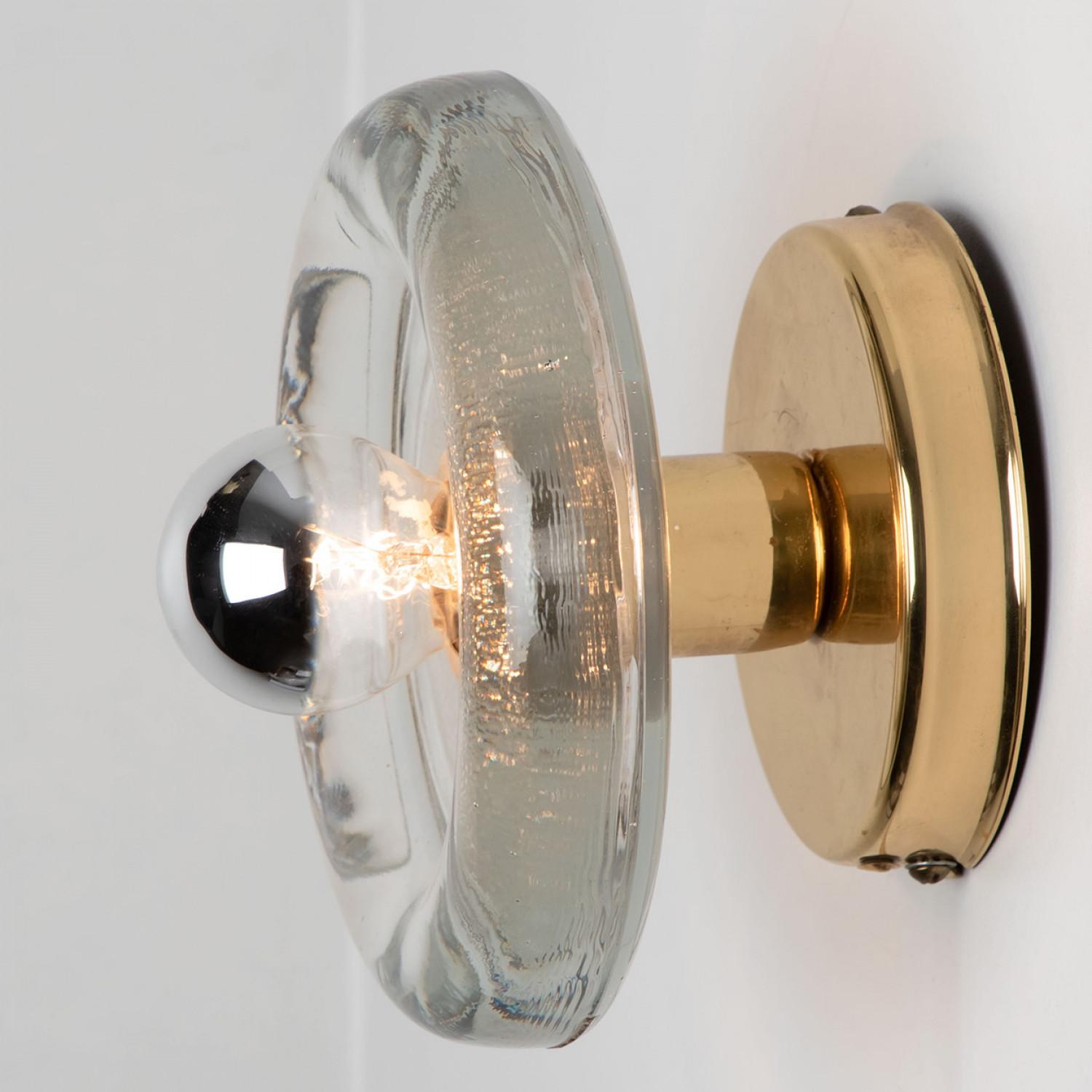 
A pair of Putzler wall light in sculptural glass on a round brass frame, circa 1970s, Germany. A clear design, with modern materials.

This modernist design is focused on the textured round thick glass glass, when illuminated and with use of mirror