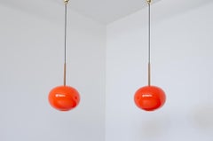 Pair of pendant chandeliers with wooden stem and red blown glass diffuser.