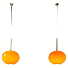 Pair of pendant chandeliers with wooden stem and red blown glass diffuser.