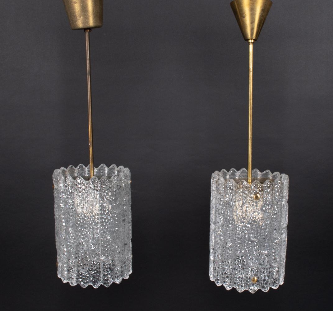 Exquise paire de lampes suspendues cylindriques de Carl Fagerlund dans son style caractéristique, chacune composée de deux panneaux incurvés en verre texturé épais suspendus à de simples tiges en laiton.

REMARQUE : Les dimensions indiquées se