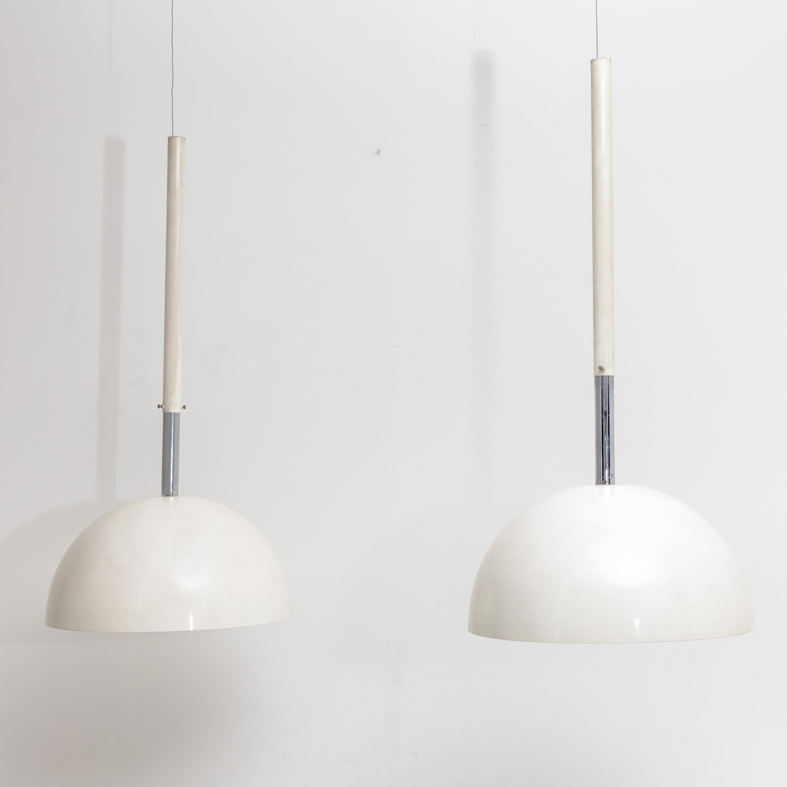 Pair of pendant lamps with white lacquered dome-shaped lampshades on cylindrical rods.