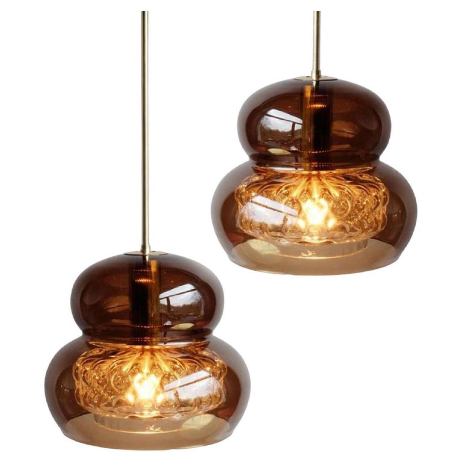 A rare pair of elegant pendant lights in smoke/brown colored glass with brass details from world famous Orrefors Glas and designed by renowned glassware designer Carl Fagerlund.

Dimensions height overall 35.4