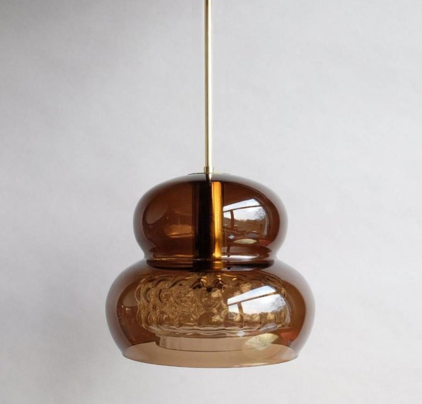 Una rara coppia di eleganti lampade a sospensione in vetro color fumo/marrone con dettagli in ottone di Orrefors Glas, famosa in tutto il mondo e progettata dal famoso designer di cristalli Carl Fagerlund.

Dimensioni altezza complessiva 35,4