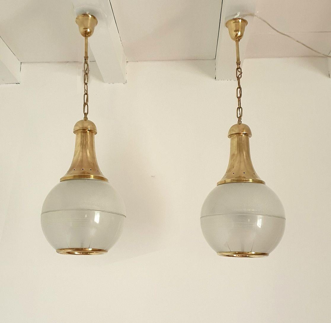 Pair of Mid-Century Modern pendant lights, by Caccia Dominioni, attributed to Azucena Italy 1950s.
The pair of Italian lanterns is made of a Holophane glass diffuser and brass mounts.
The pendant chandeliers have 3 lights each and are professionally