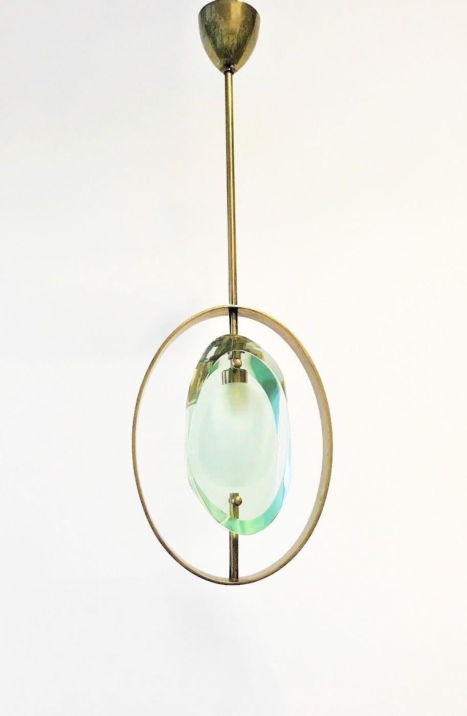 Very elegant pair of pendants by Max Ingrand for Fontana Arte, Model 1933, Italy, 1961. Organically shaped double lens cut panels of thick Murano polished glass with etched glass centers fitted within a natural brass ring suspended from brass