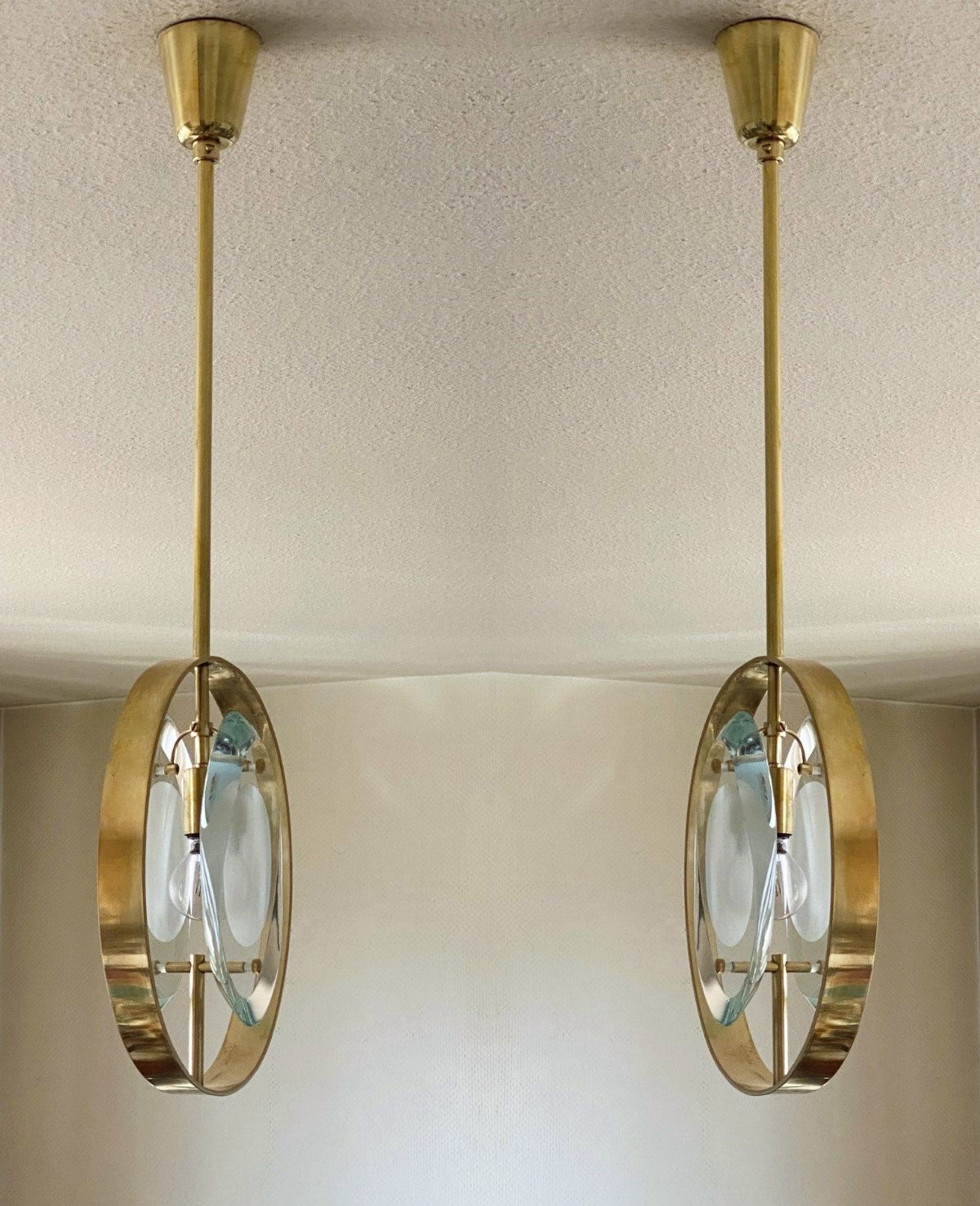 Una coppia di  pendenti dal design iconico di Max Ingrand per Fontana Arte, Modello 1933, Italia, 1961. Pannelli a doppia lente di forma organica in vetro di Murano lucido e profilato, con centri sabbiati, inseriti in un anello di ottone naturale