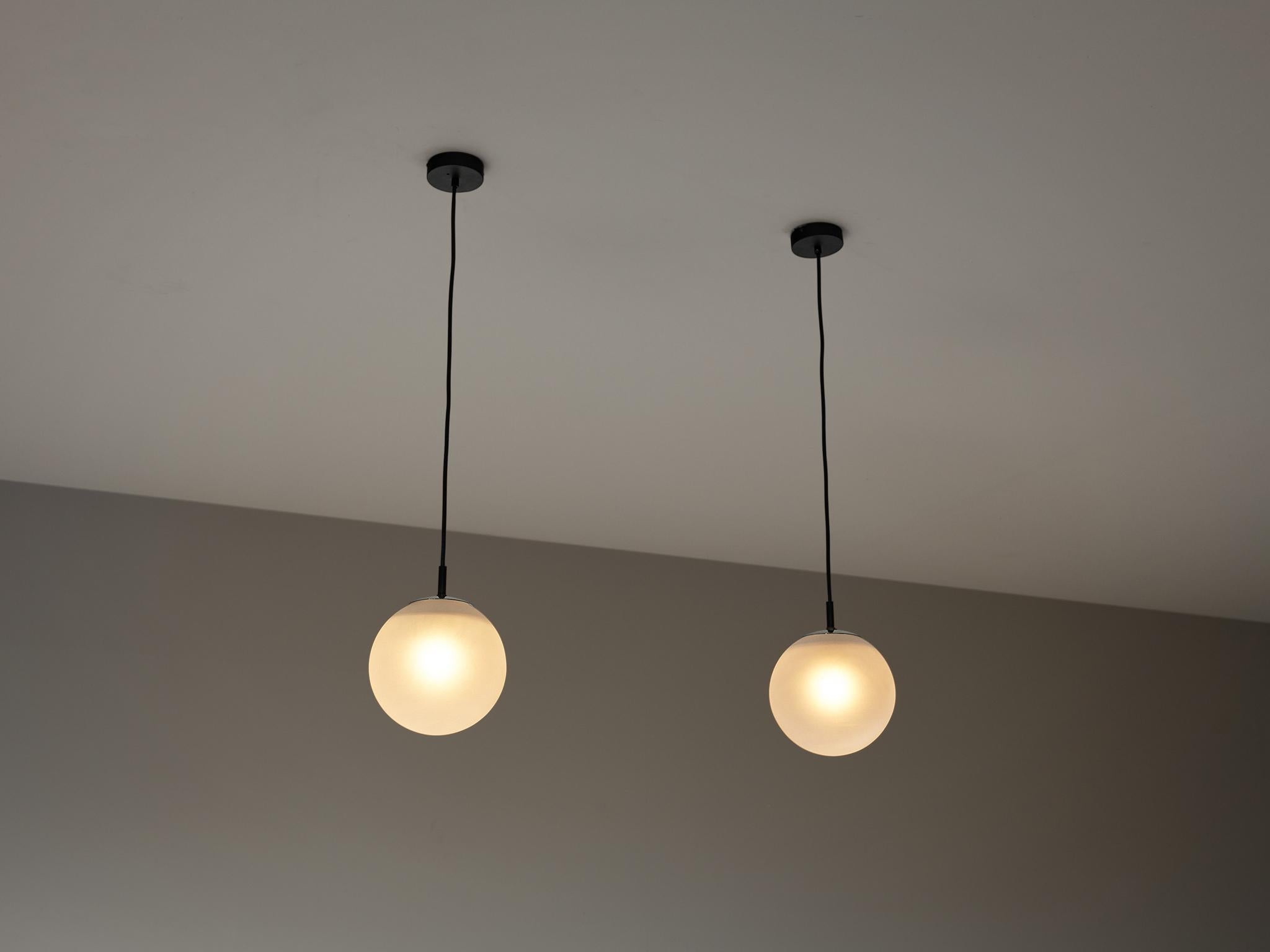 RAAK Amsterdam, pendants, satin glass, metal, Europe, 1970s.

This atmospheric set of pendant lamps features each a frosted glass orb, casting a gentle and soothing light tone that imbues the space with a vibrant atmosphere. The lamps can be hung