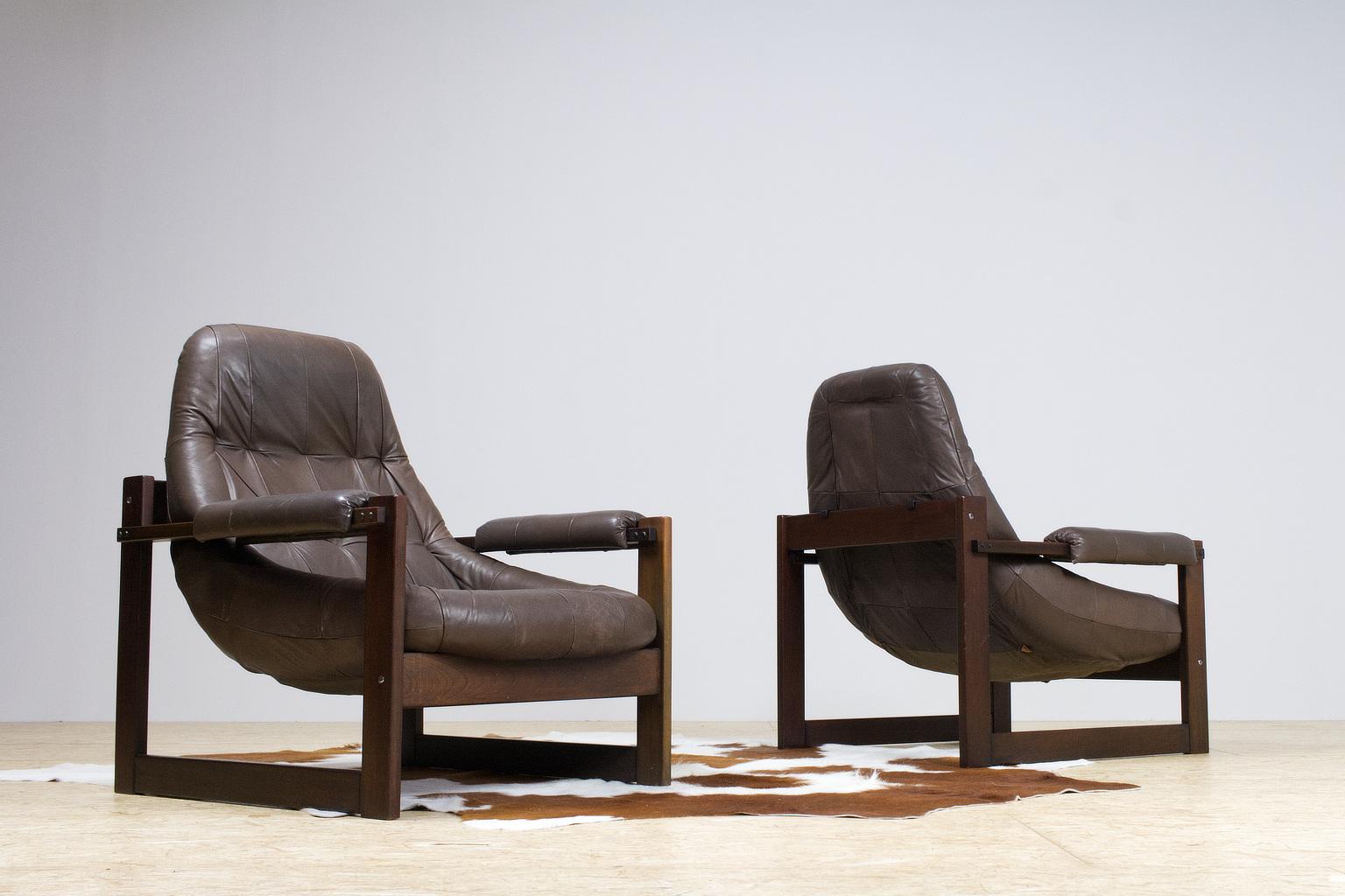 Great set of matching leather lounge chairs by Percival Lafer, 1960-1970s Brazilian modern. The massive wooden cubical frame holds the 'floating' dark brown leather shell. The hard wooden construction draws the most attention, which is a typically