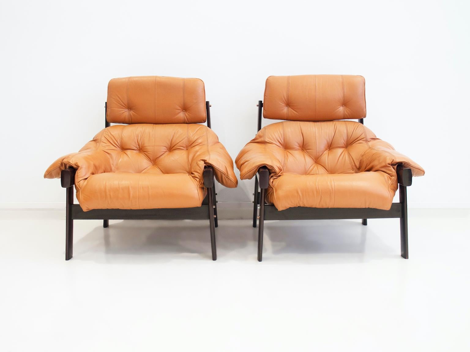 Pair of armchairs with footrests designed by Percival Lafer. Hardwood structure, caramel colored leather upholstery. Manufactured by Lafer MP in Brazil, circa 1970. Footrest measurements: W 71 x D 53 x H 42 cm.