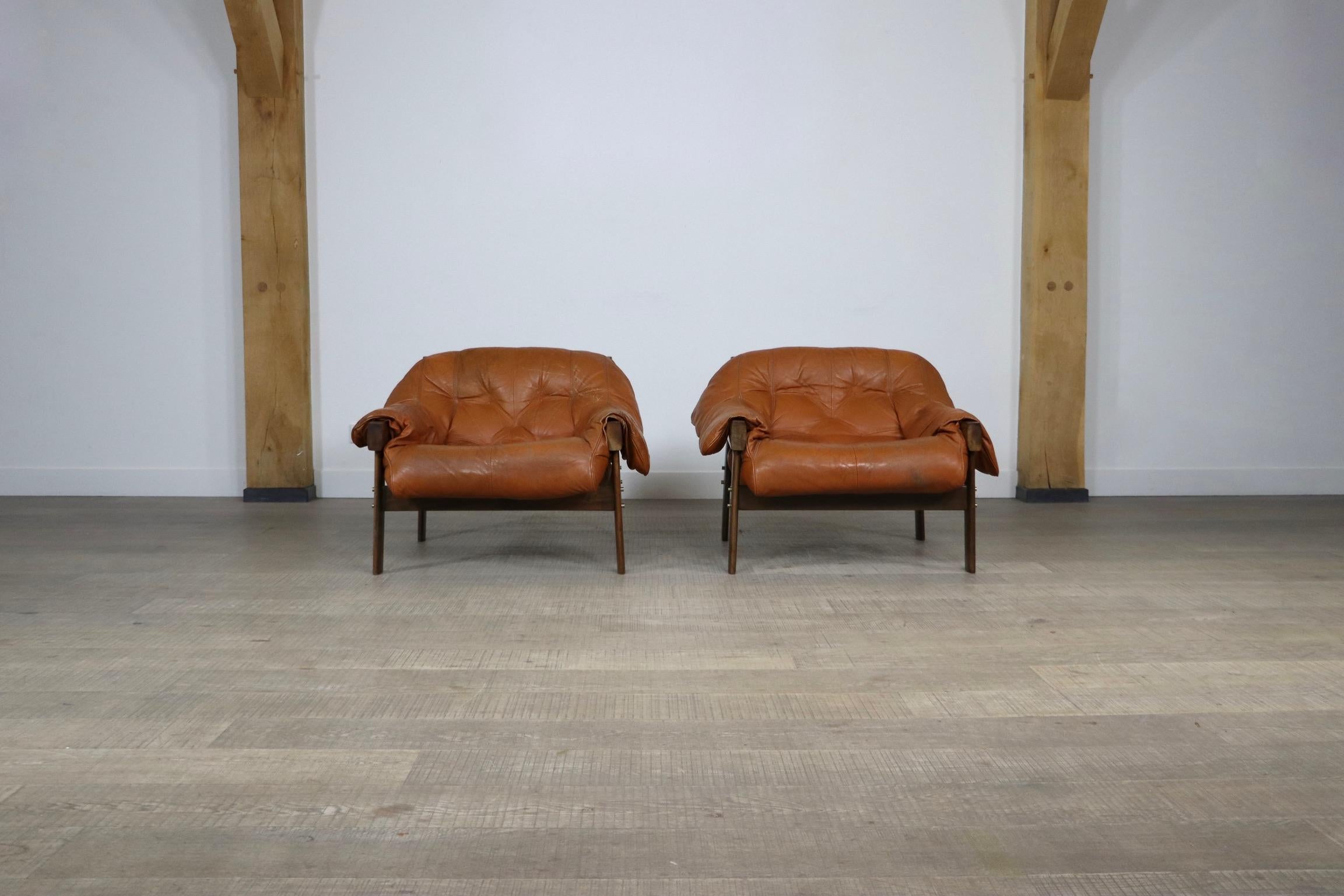 Beautiful pair of MP-41 lounge chairs in original cognac leather and jacaranda wood frame, designed by Percival Lafer for MP Lafer, 1970s. Both chairs have original mark in the leather strap on the back. 
This highly comfortable and great looking