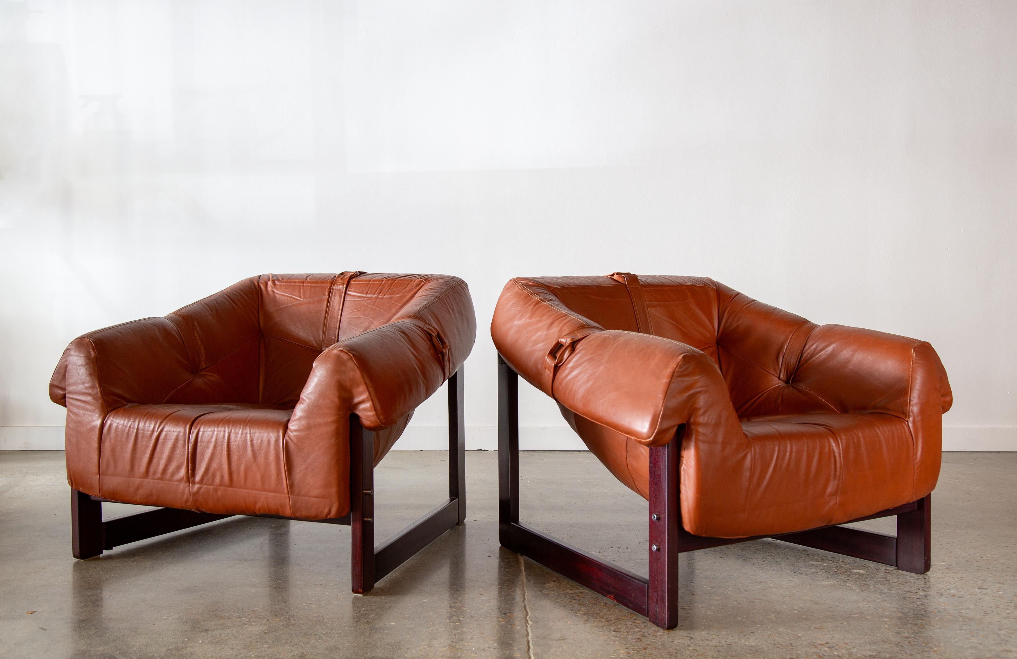 Extra comfortable pair of leather and rosewood lounge chairs designed by Percival Lafer for Brazil Industries Corp. Model MP93 chairs with Brazilian rosewood frames and rubber straps which support a foam filled leather cushion that wraps the frame.
