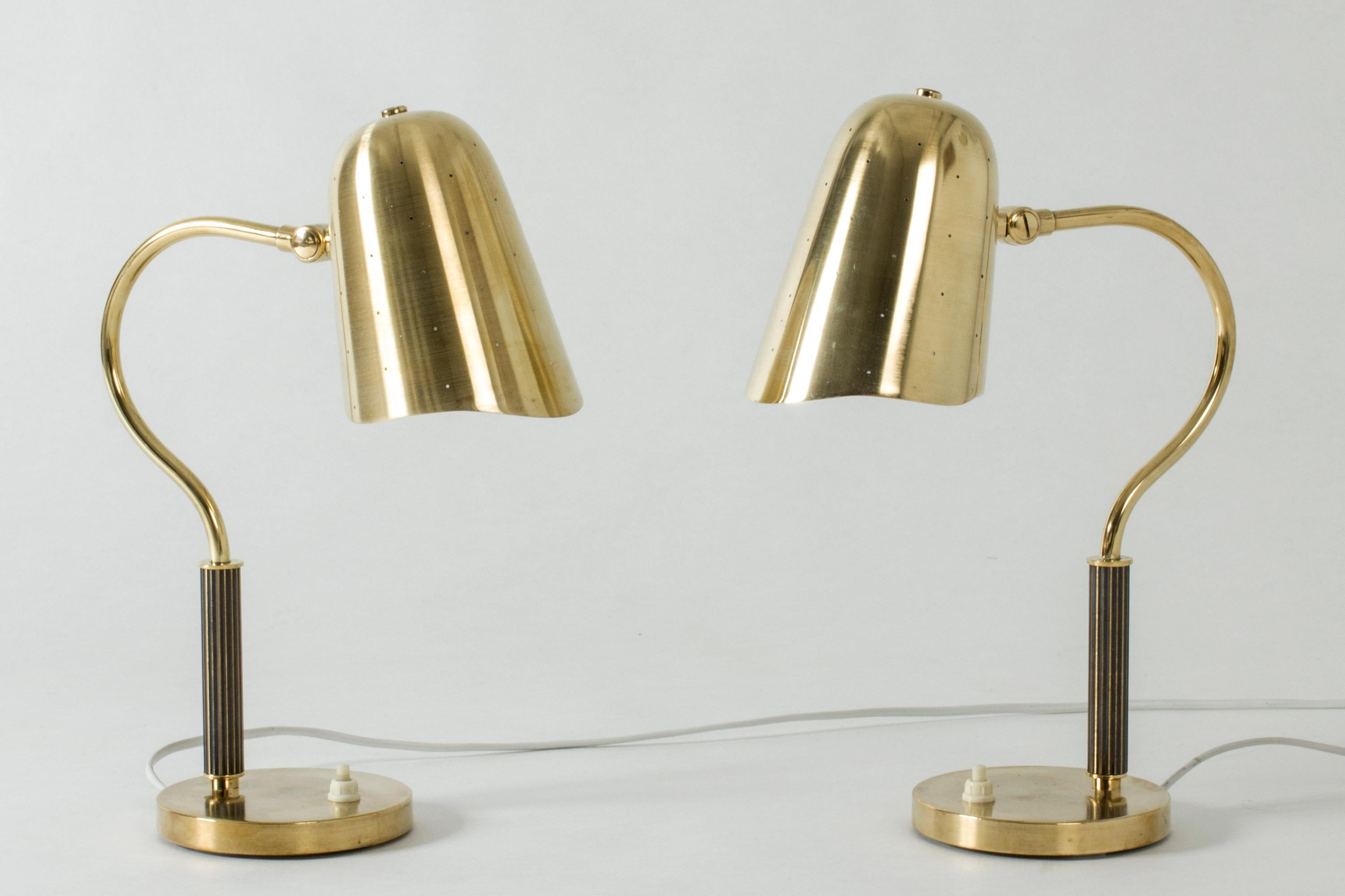 Pair of elegant brass table lamps, perfect for bedside tables. Perforated shades that let the light out like little stars when lit. Curved necks and handles embossed with stripes.