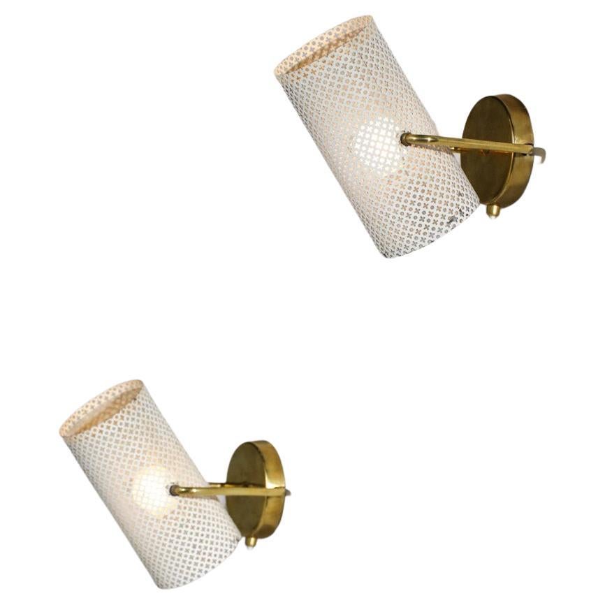 Pair of sconces from the 50's in the style of Pierre Guariche's work. Structure in solid brass, lampshade in beige lacquered perforated metal (original paint). Shade adjustable from top to bottom. Very nice model of wall lamp, electrical system
