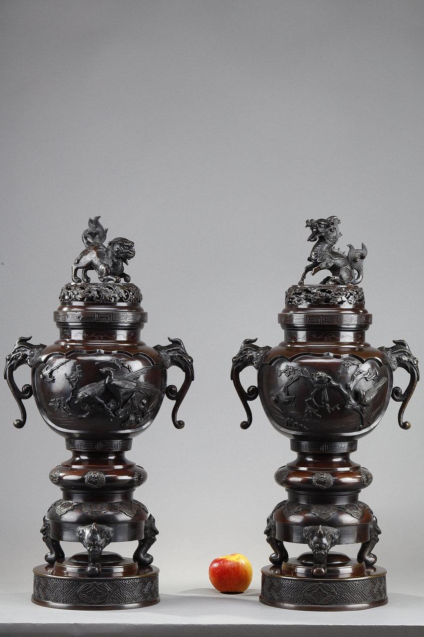 Important pair of Far Eastern perfume burners in patinated bronze. The handles and grips of the lids are decorated with dogs and dragons. The two sides are richly decorated in relief with birds and branches, resting on a tripod base with hooves. The