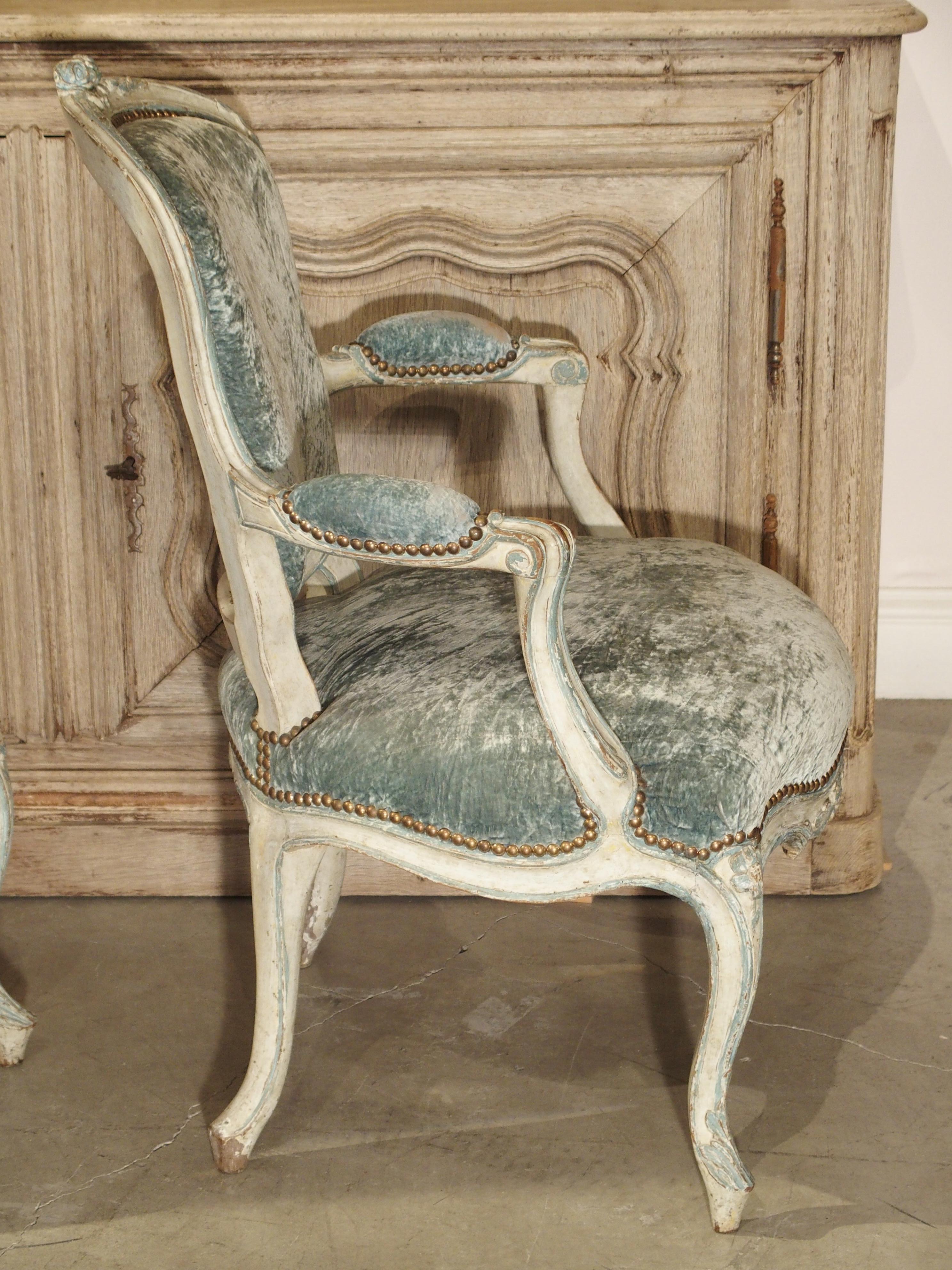Measures: Back height 35, arm height 24 1/4, seat height 17 5/8, seat width 21 5/8, seat depth 18, total depth 25, width 26.

This is a wonderful pair of rare French blue and cream colored cabriolet chairs from the mid-1700s. They are completely