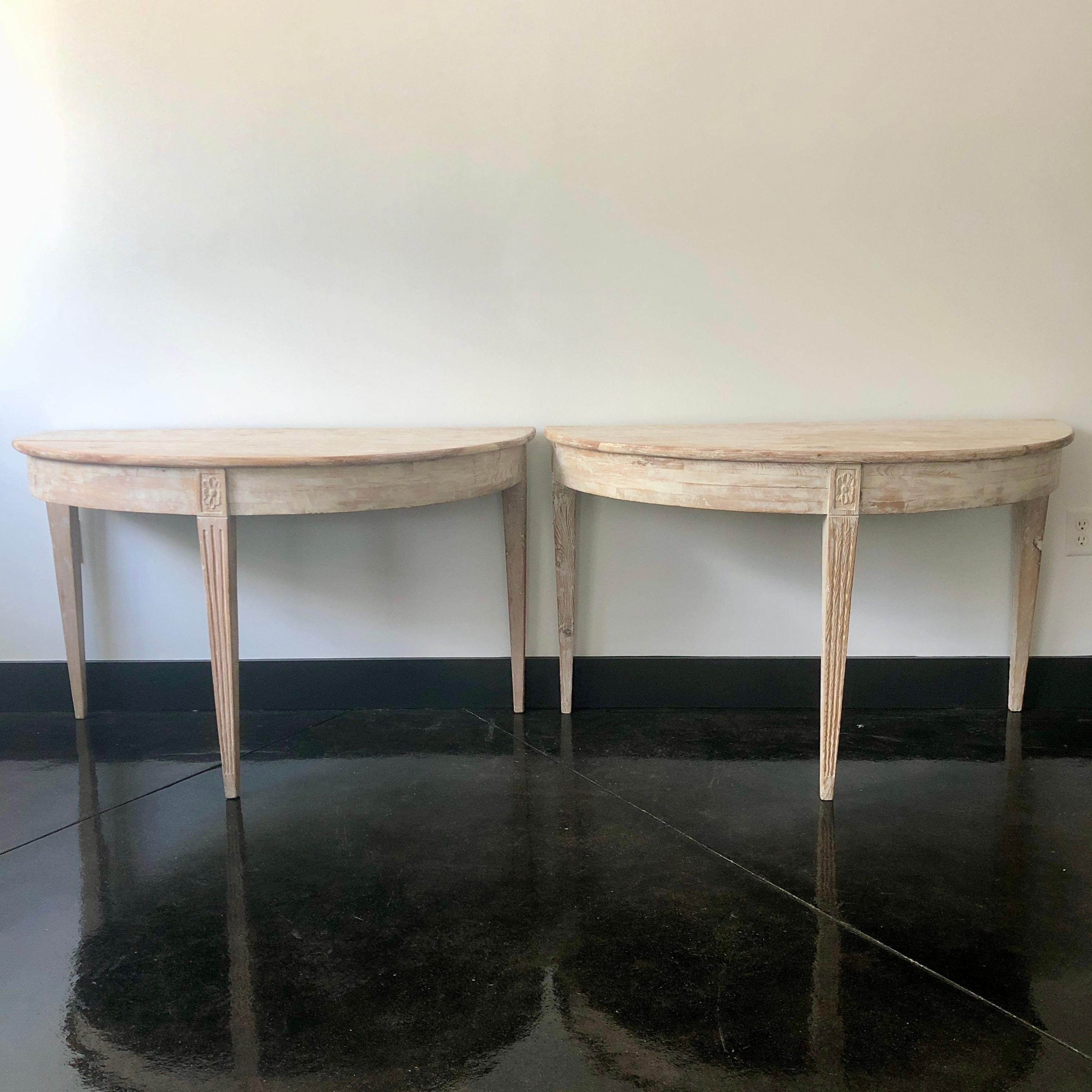 Pair of Swedish Gustavian period demilune console tables with wide rounded apron and florets on the corner blocks. Elegant tapered and fluted legs.
Many layers of newer paint scraped to its most original finish.
Stockholm, Sweden, circa 1820.