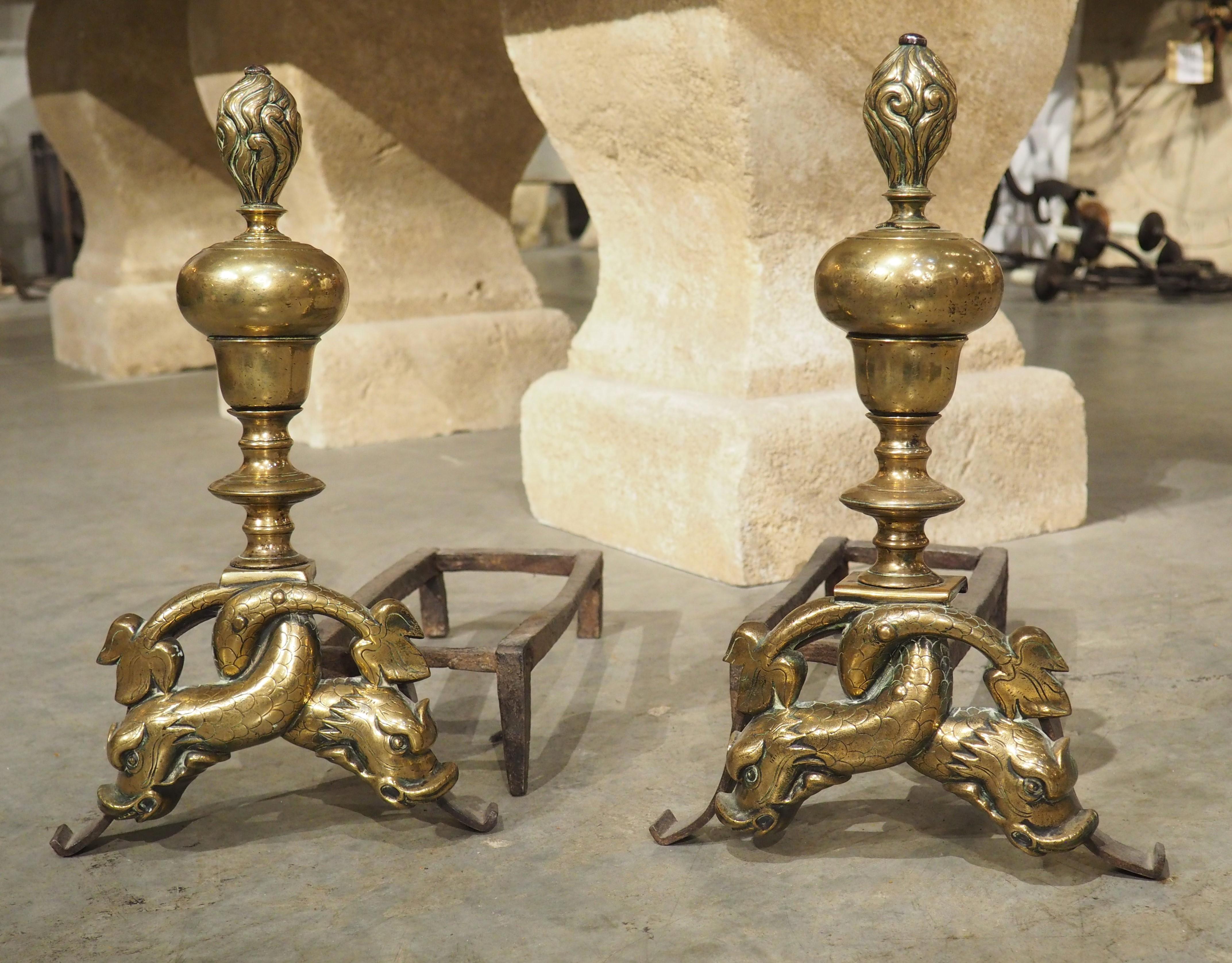 This rare pair of French bronze andirons is from the period of Louis XIV (1643-1715), which in France, was the period that the andiron reached its greatest artistic development. The motifs are intertwining dolphins with incised scales and stylized