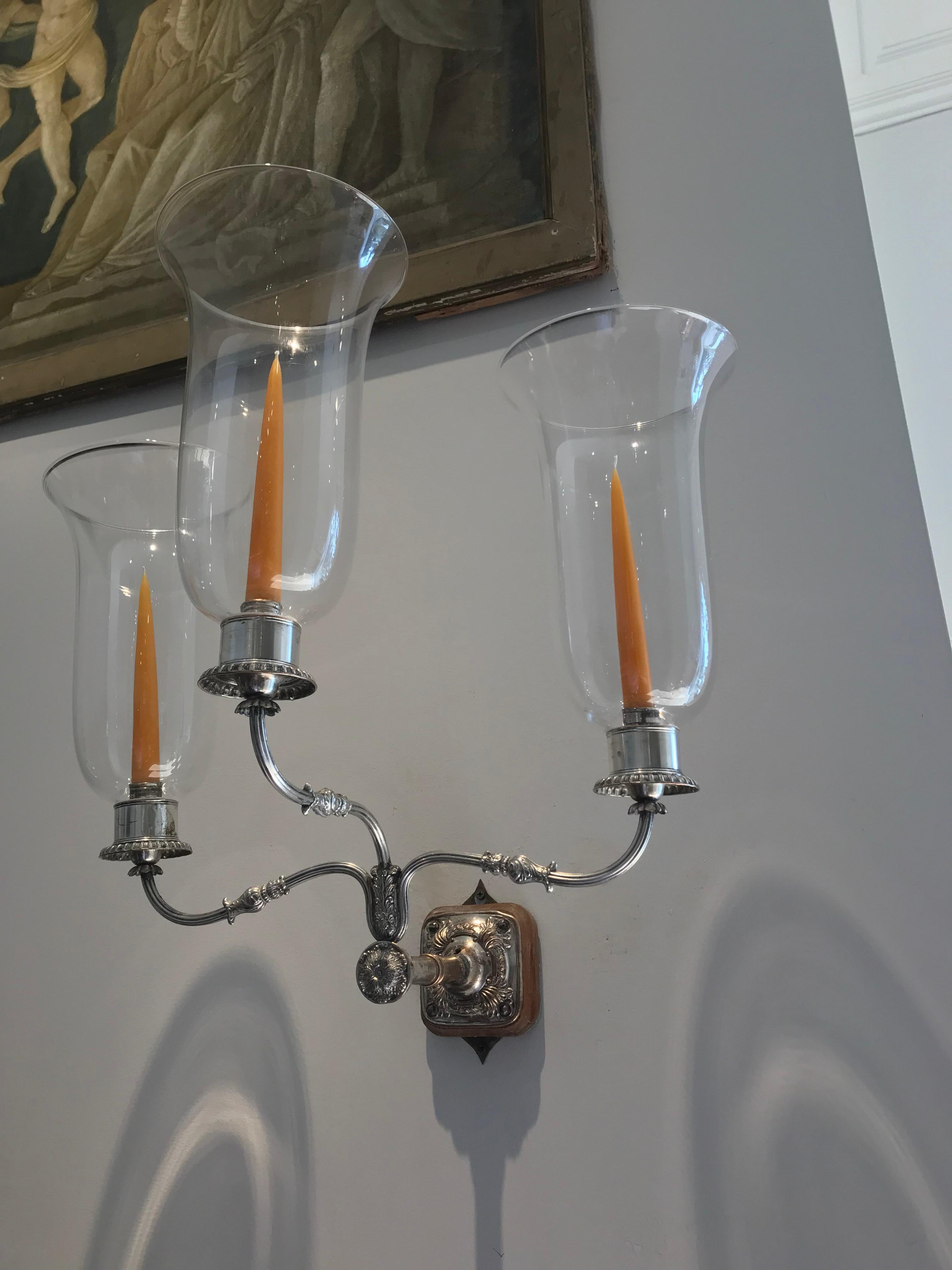 Pair of period English Regency sheffield silver wall sconces

Three arm pair of wall sconces with hurricane glass shades
Neoclassical work
Can be French Wired.