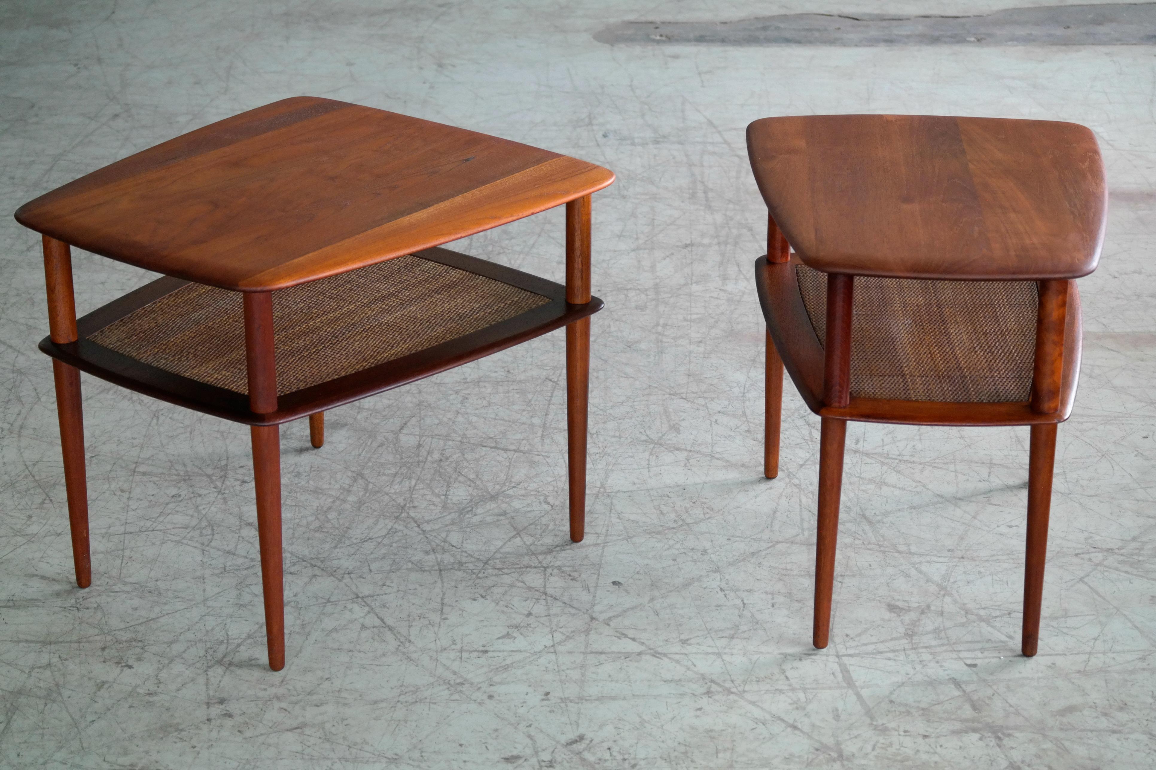 Fantastic pair of very hard to find teak Danish Modern end tables designed by Peter Hvidt for France and Son. Crafted in solid teak with a woven cane magazine shelf under tabletop raised on slim conical legs. One table is slightly narrower in the