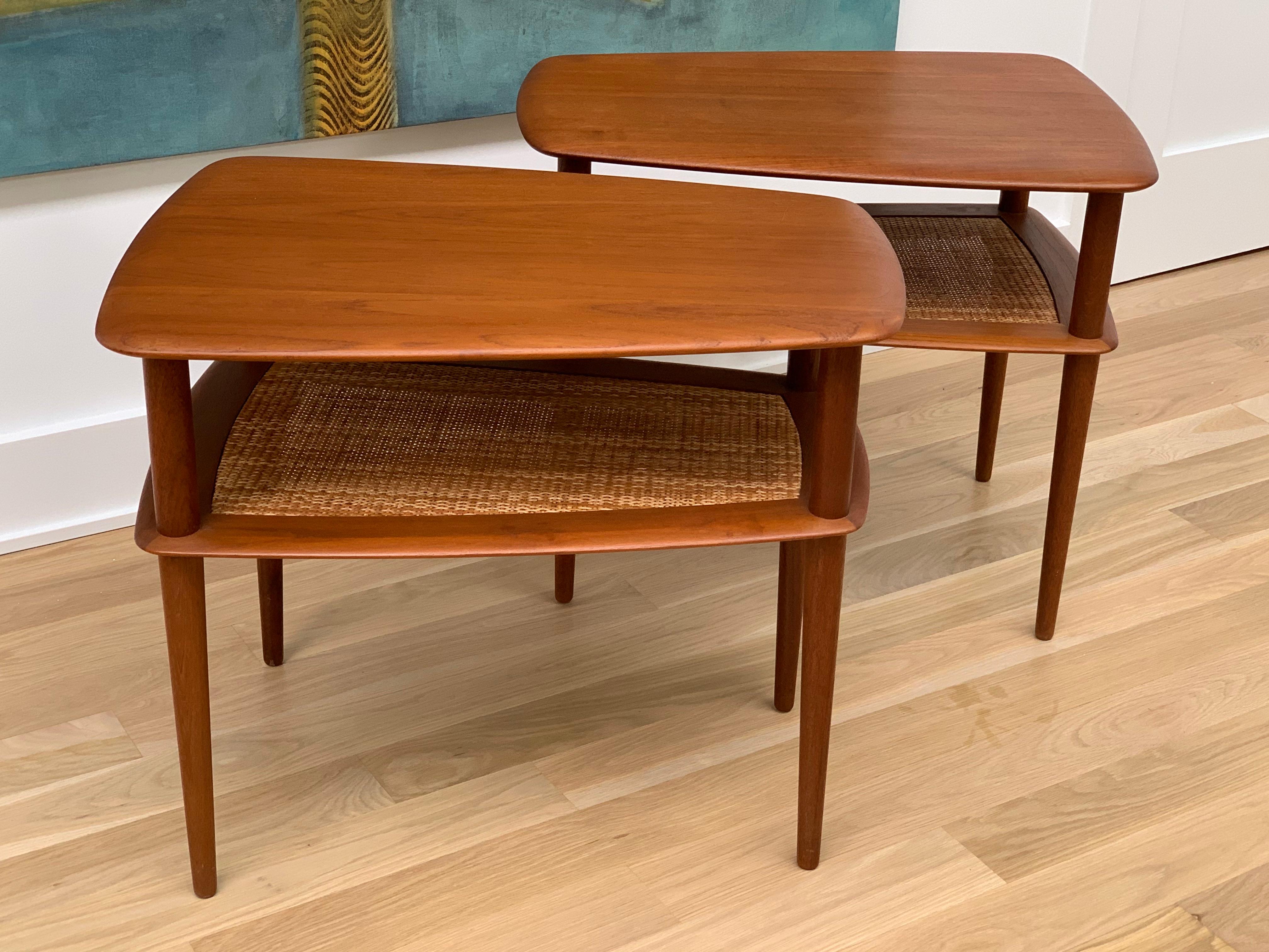 Matched pair of teak side tables with rush shelf designed by Peter Hvidt and Orla Molgaard-Nielsen for France and Sons. All teak, with a magazine shelf with inset of rush. Design details of tapered legs, round soft edges. The tables are designed