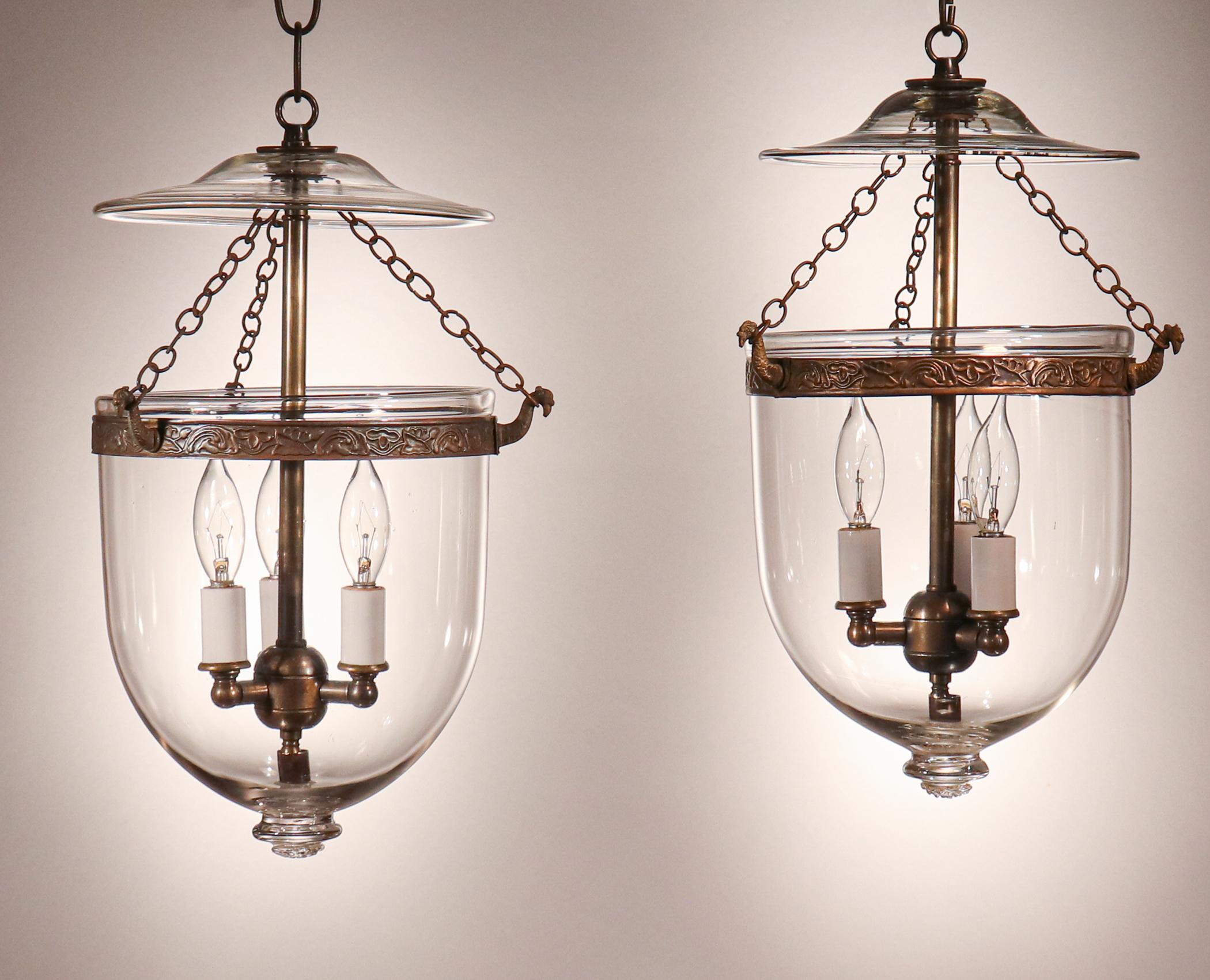 Petite and sweet, these antique English hand blown glass bell jar lanterns are a rare find. Perfect for lower ceiling heights and smaller spaces, these circa 1890 lanterns feature original smoke bells/lids and chains. The brass bands, which have an