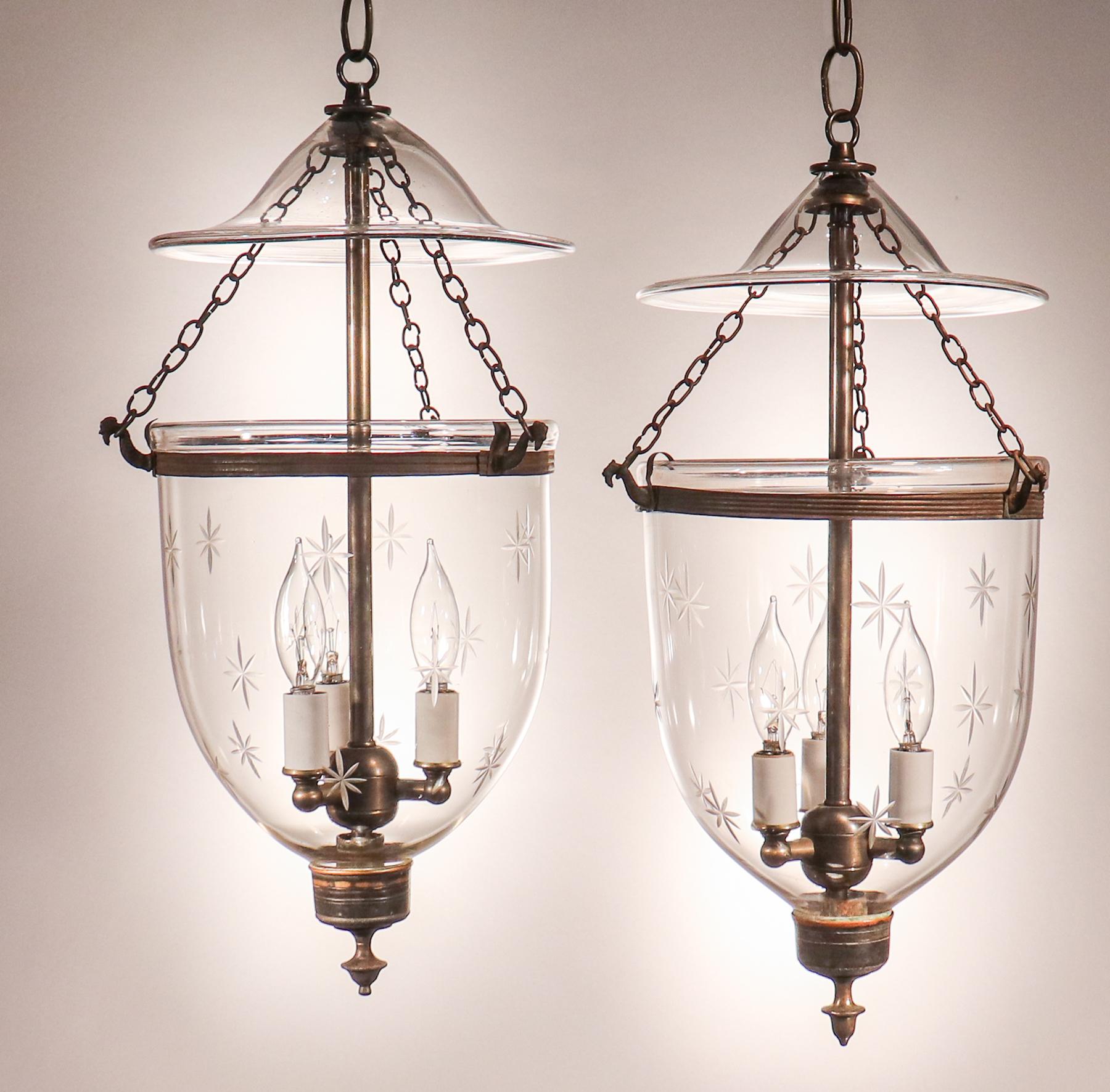 A pair of petite bell jar lanterns with lovely form and a finely etched star motif. These circa 1870 lanterns feature original brass bands and finials/candle holder bases with great patina. The pendant lights have been newly electrified, each with a