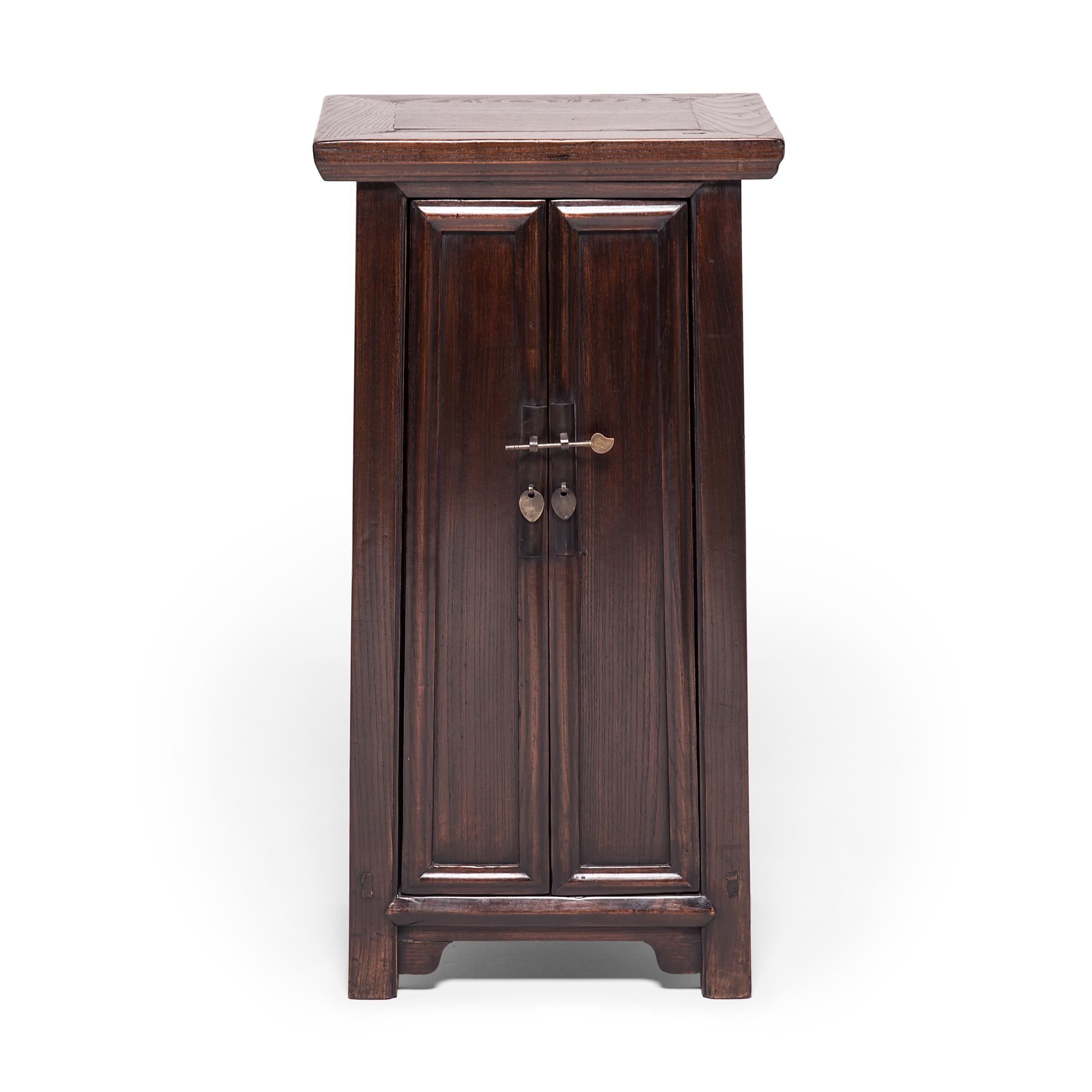This striking pair of petite elmwood cabinets was constructed in the early 20th century by an artisan in China's Shanxi province. Called “noodle” for the rounded wood molding that outlines its doors and frame, the cabinets have an austere beauty,