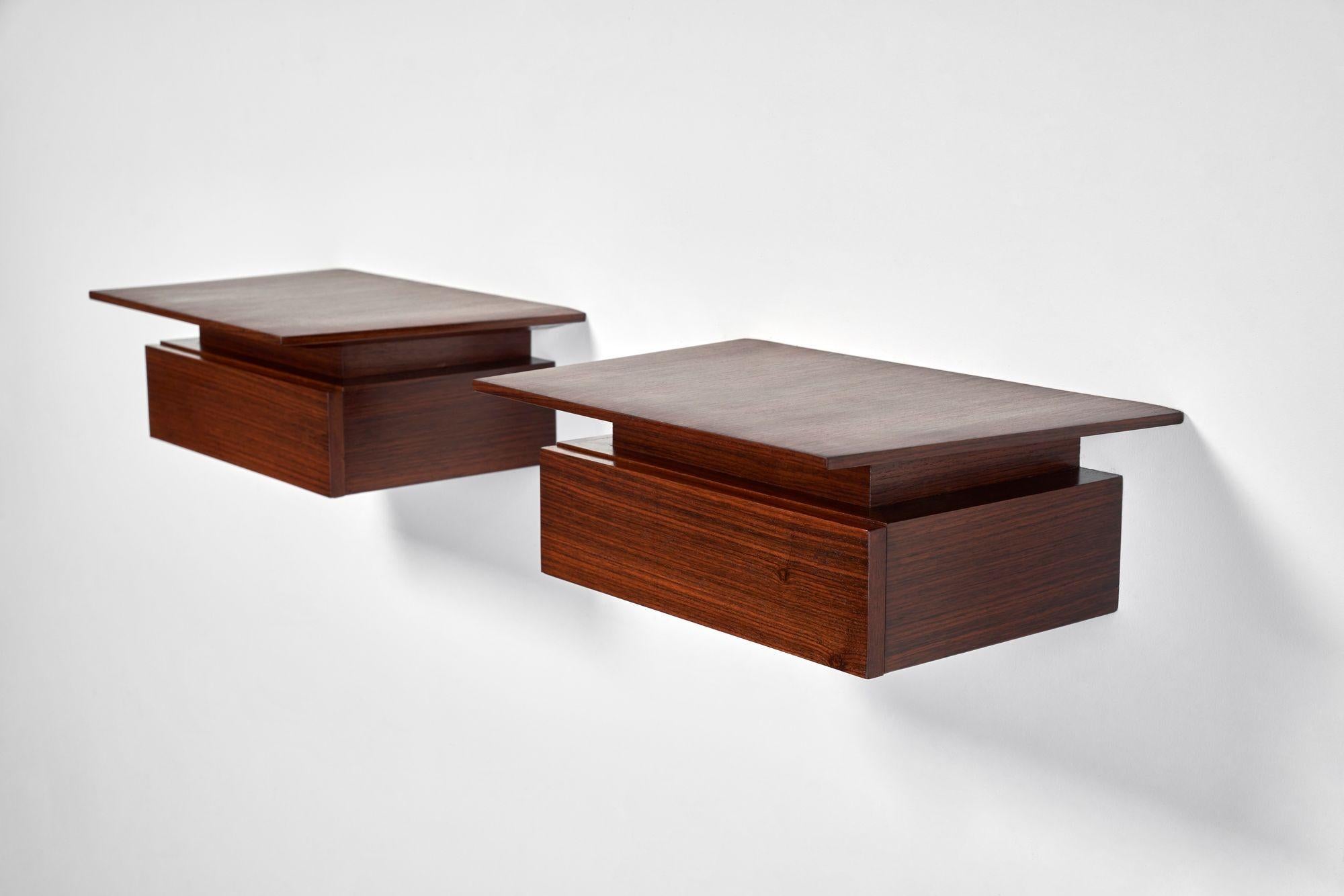 Paire de tables de nuit ou de chevets suspendus/muraux en palissandre (vers les années 1960, Danemark).
Une forme minimale et élégante avec des surfaces trapézoïdales flottant au-dessus de tiroirs simples.
Deux supports métalliques sont présents à