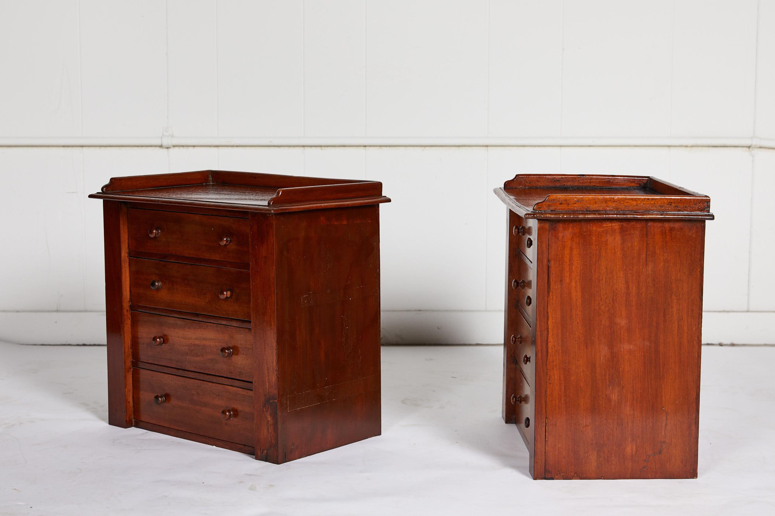 19th century charming English pair of miniature mahogany four-drawer chests with gallery lined tops and wooden knobs.