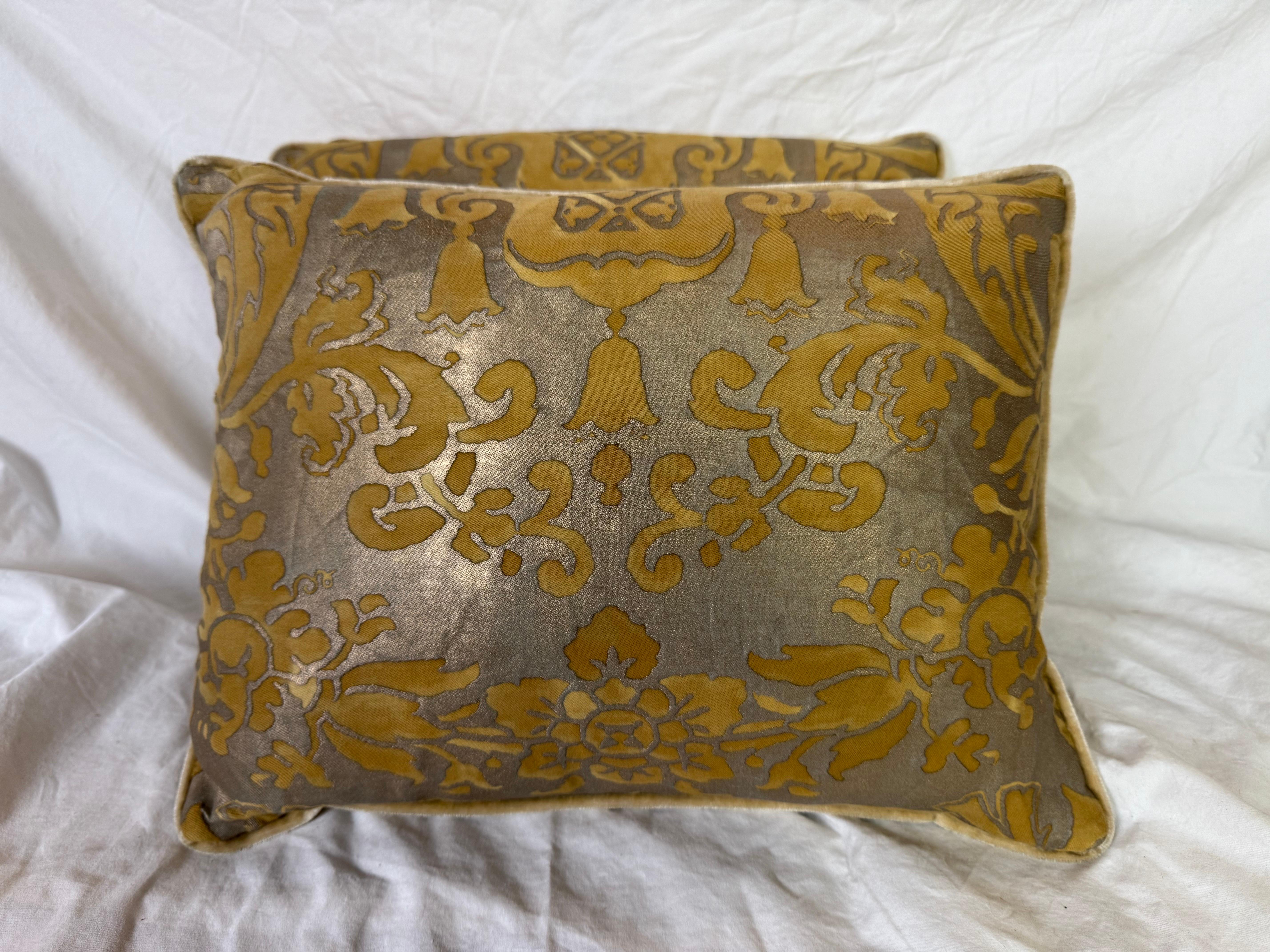 Cette paire de coussins Fortuny présente un motif classique audacieux et élégant dans un riche ocre doré, peint au pochoir sur un fond taupe argenté. Le devant du textile en coton de Fortuny présente un motif symétrique de fleurs stylisées et