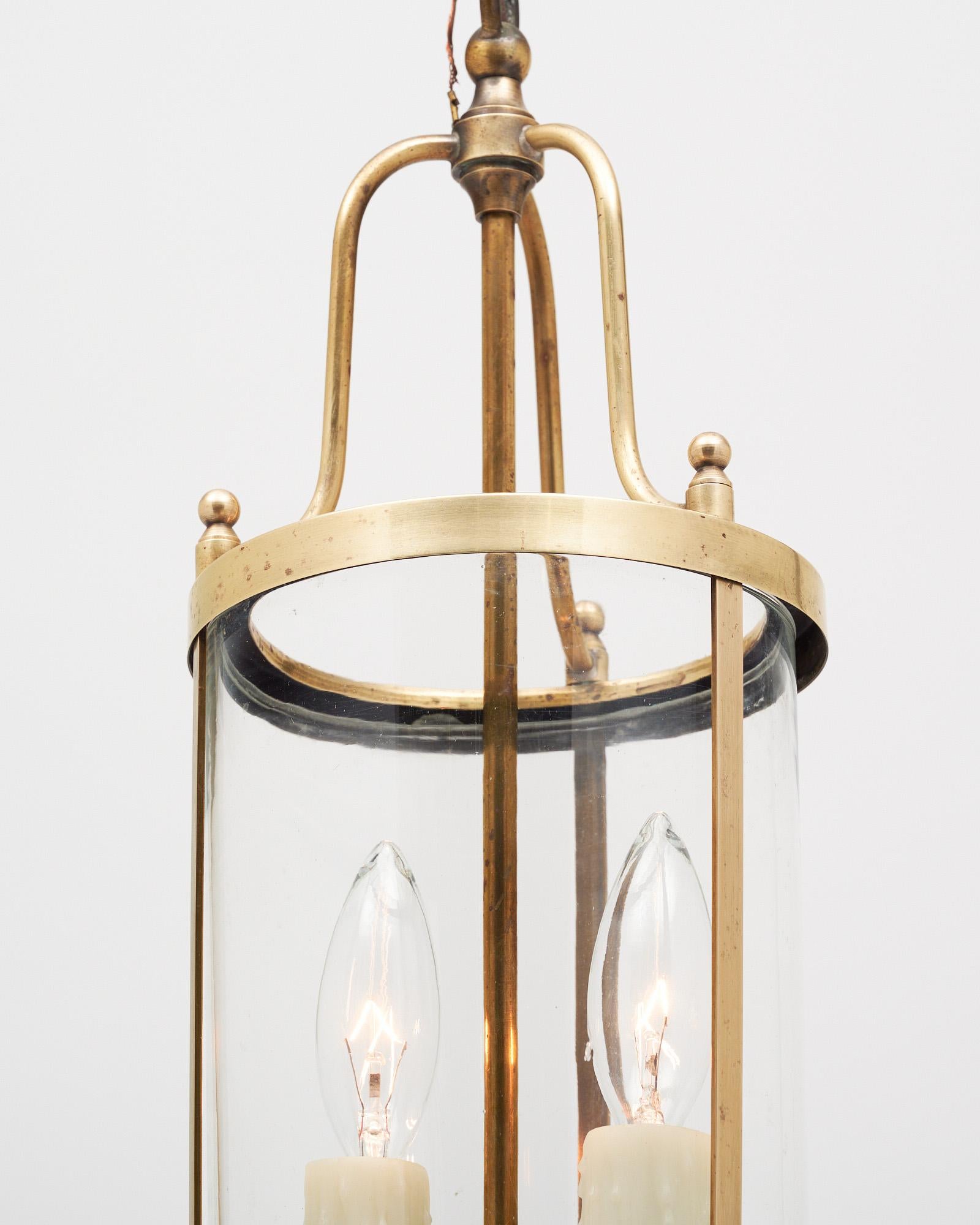 Pair of lanterns from France made with a solid brass structure and curved glass panels. There are two arms with candelabra bulbs. This petite fixture has been newly wired to fit US standards. It is in very nice antique condition with only minor