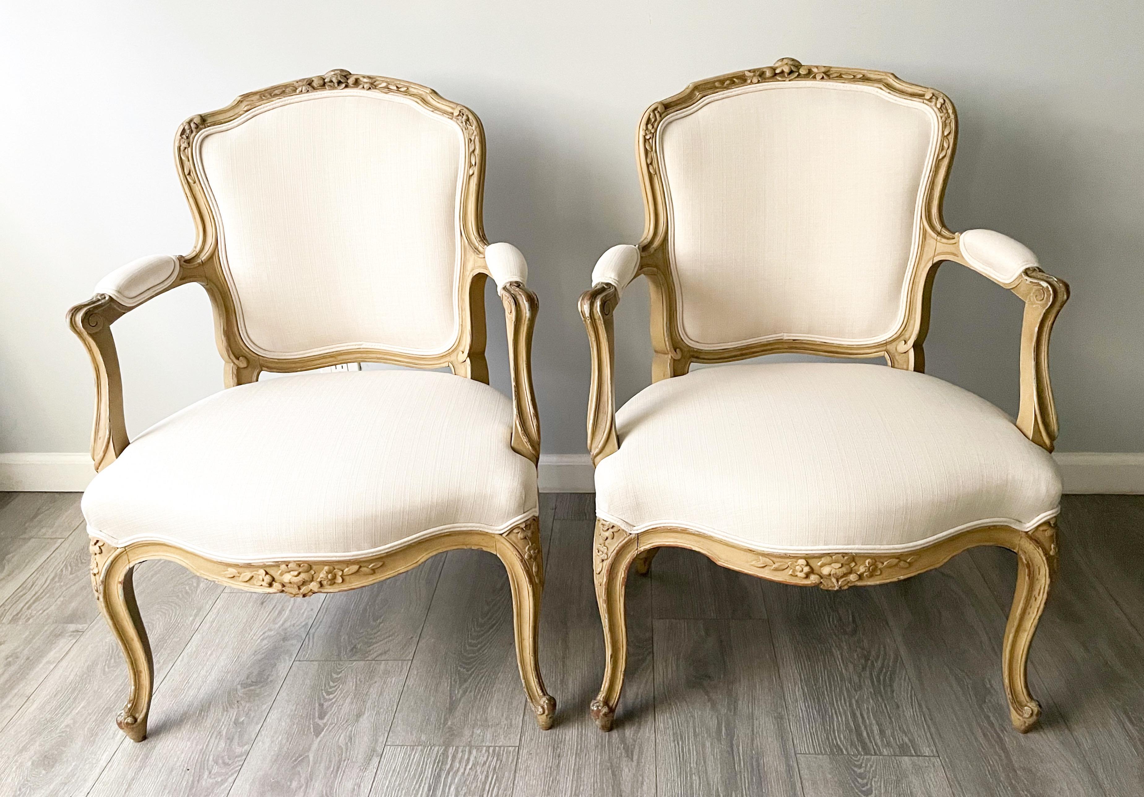 Beautiful, French 1920s petite-scale, Louis XV-style painted armchairs. 

The chairs feature delicately carved frames showing several layers of old, naturally distressed paint. New cotton linen upholstery. 

The chairs are sturdy and sound,