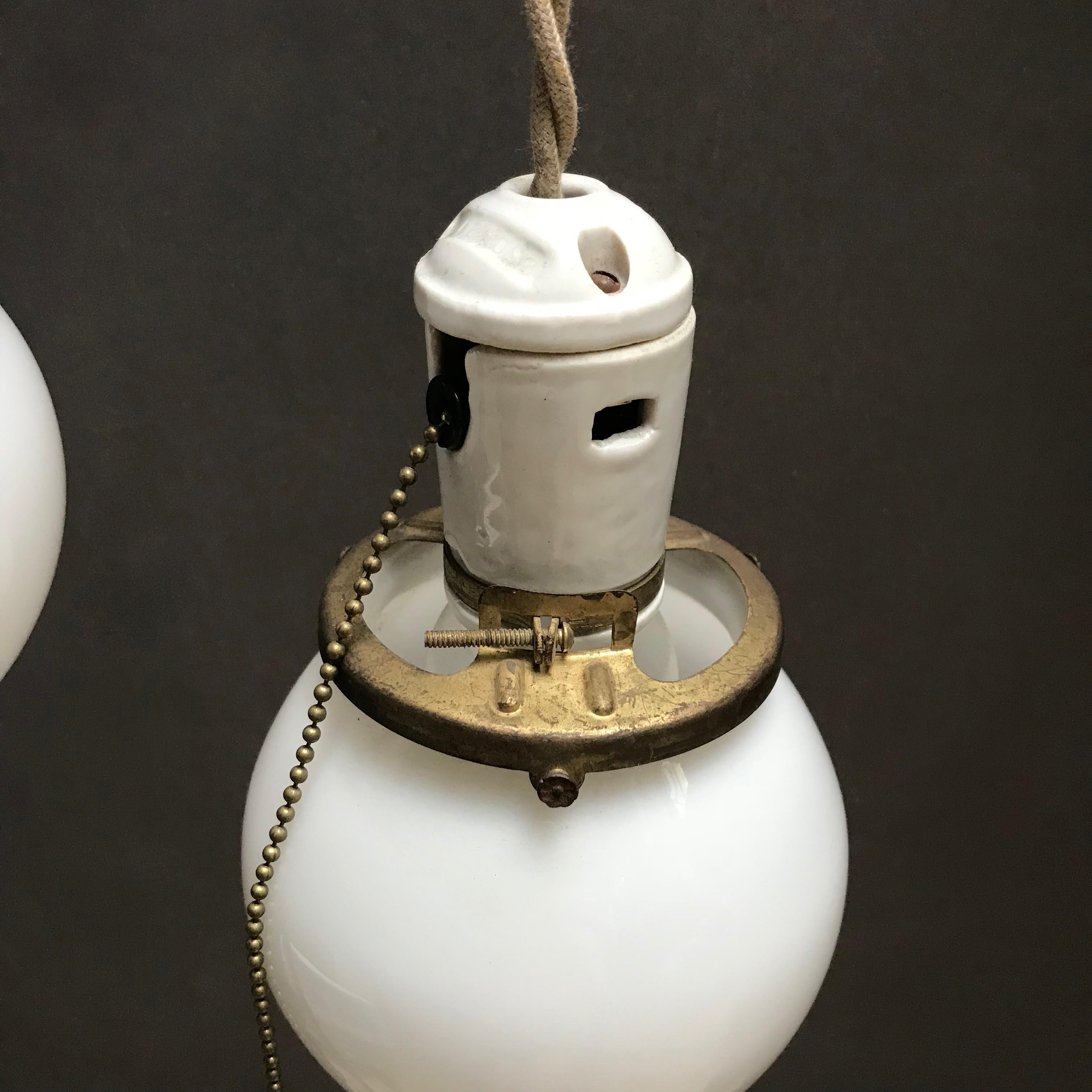 Brass Pair of Petite Industrial Milk Glass and Porcelain Globe Pendant Lights