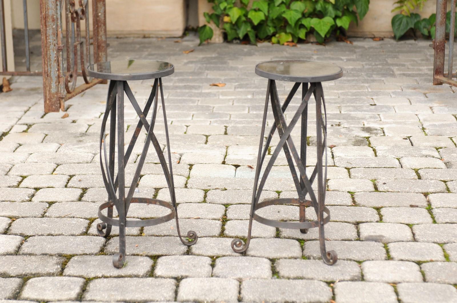 A pair of vintage Italian midcentury petite iron drink tables with mirrored top and scrolled legs. Born in the mid-20th century, each of this pair of Italian drink tables features a small mirrored top resting on a charming iron base made of