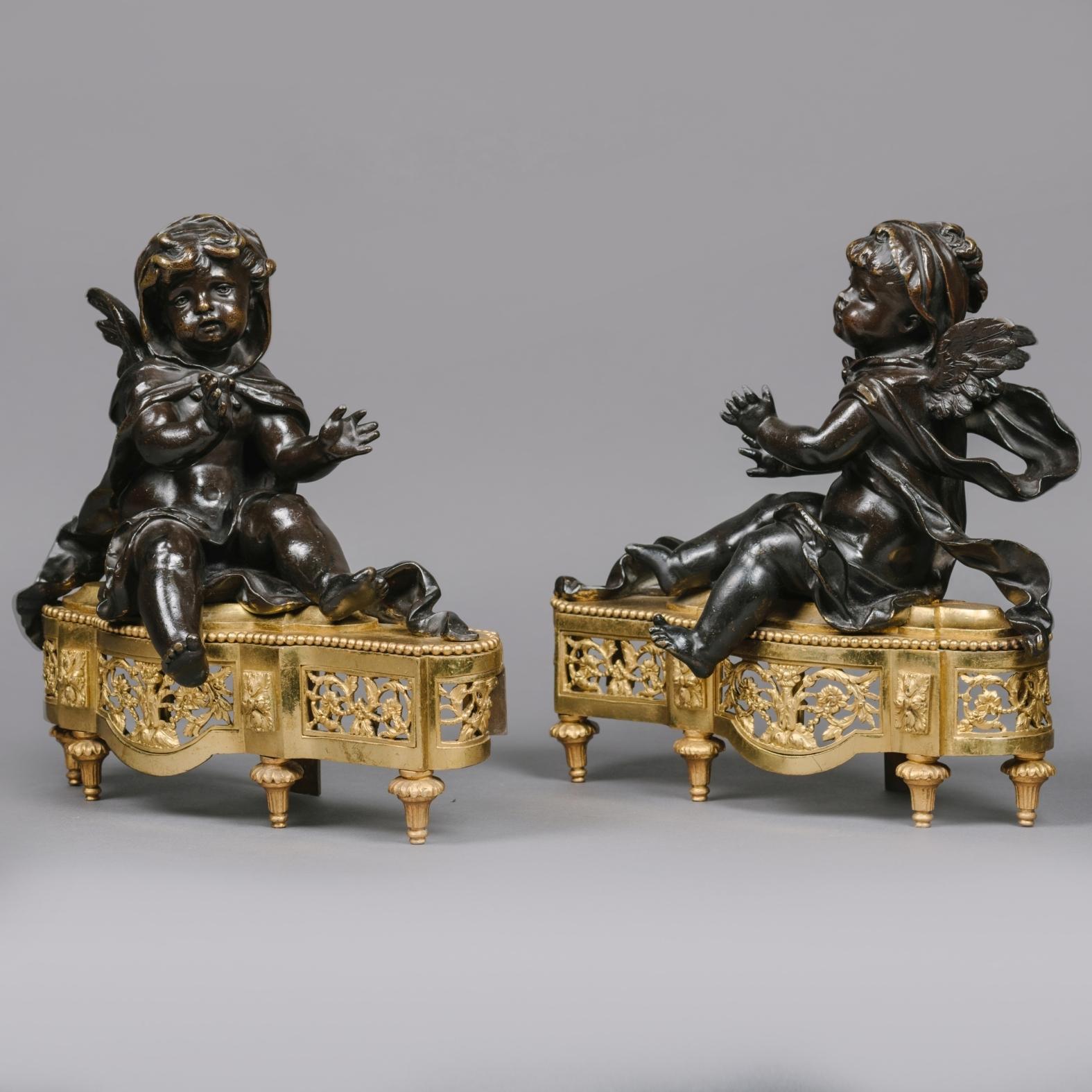 A pair of petite Louis XVI Style gilt and patinated bronze chenets. 

Each modelled as a seated winged putto with outstretched arms raised on a pierced acanthus cast gilt-bronze stand, with toupie feet. 

French, Circa 1860.