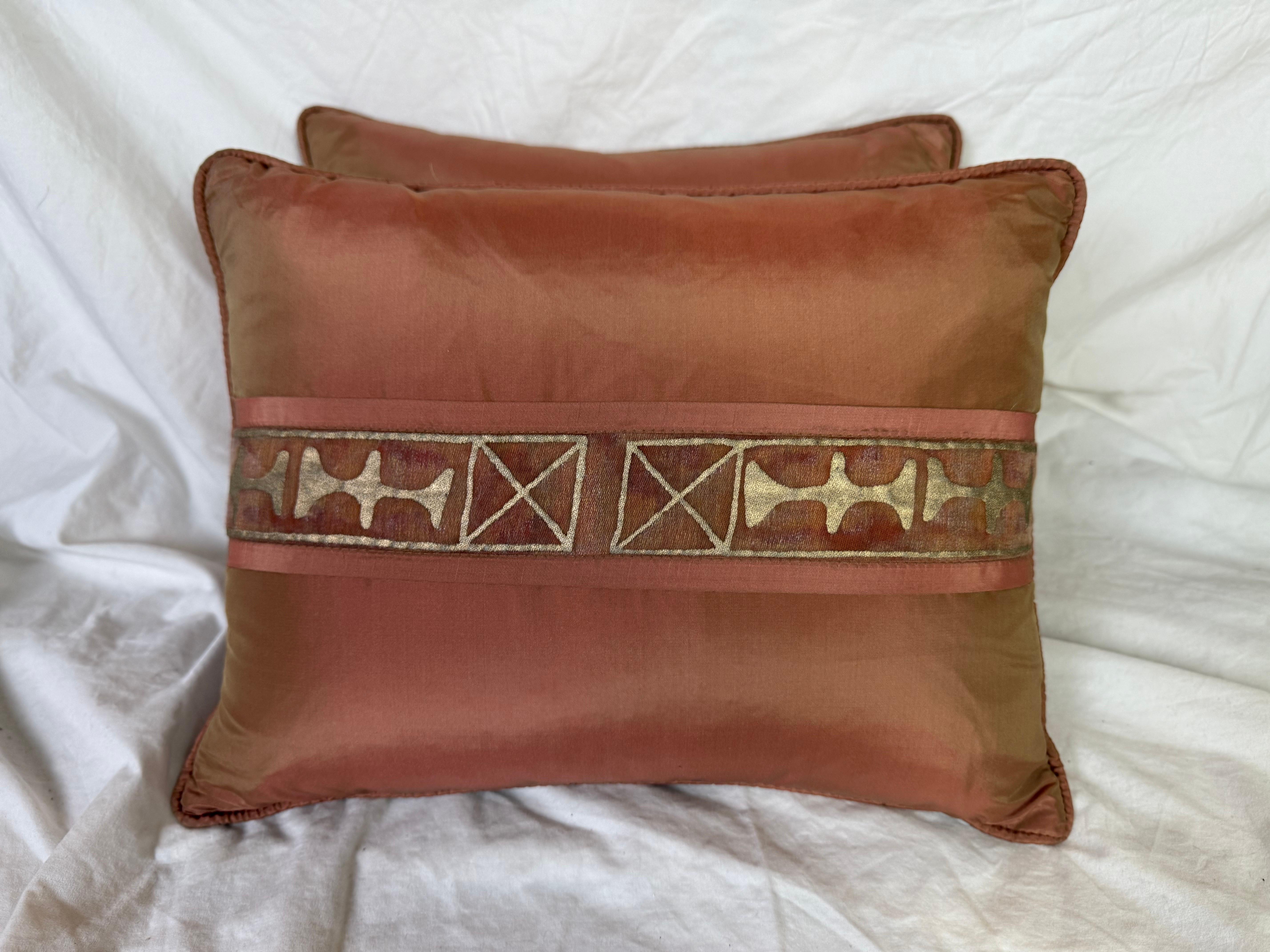 Questi lussuosi cuscini in seta presentano un disegno a righe di Fortuny. Il tessuto di base è una seta ramata ricca, calda e tenue, con una leggera lucentezza che gli conferisce un aspetto elegante e sofisticato.

Una caratteristica fascia